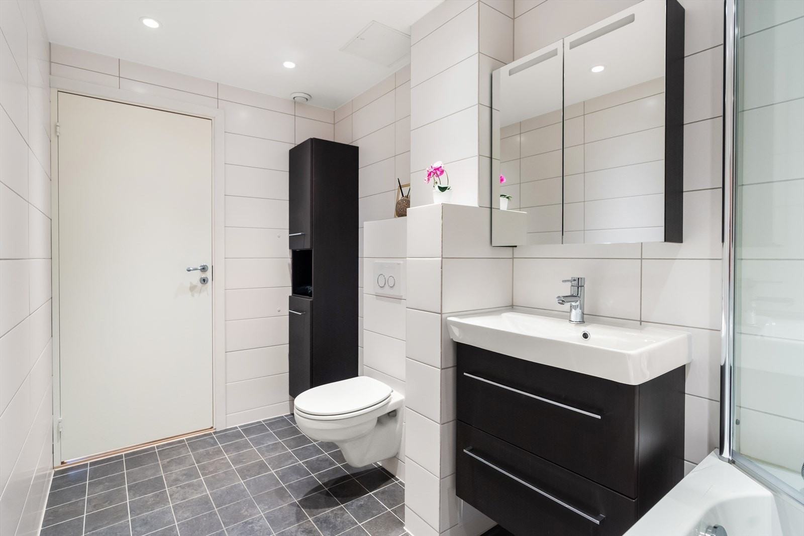 Badet har lyse fliser på veggene og mørke fliser på gulvet. Det er behagelig gulvvarme og downlights i himling. Galleribilde