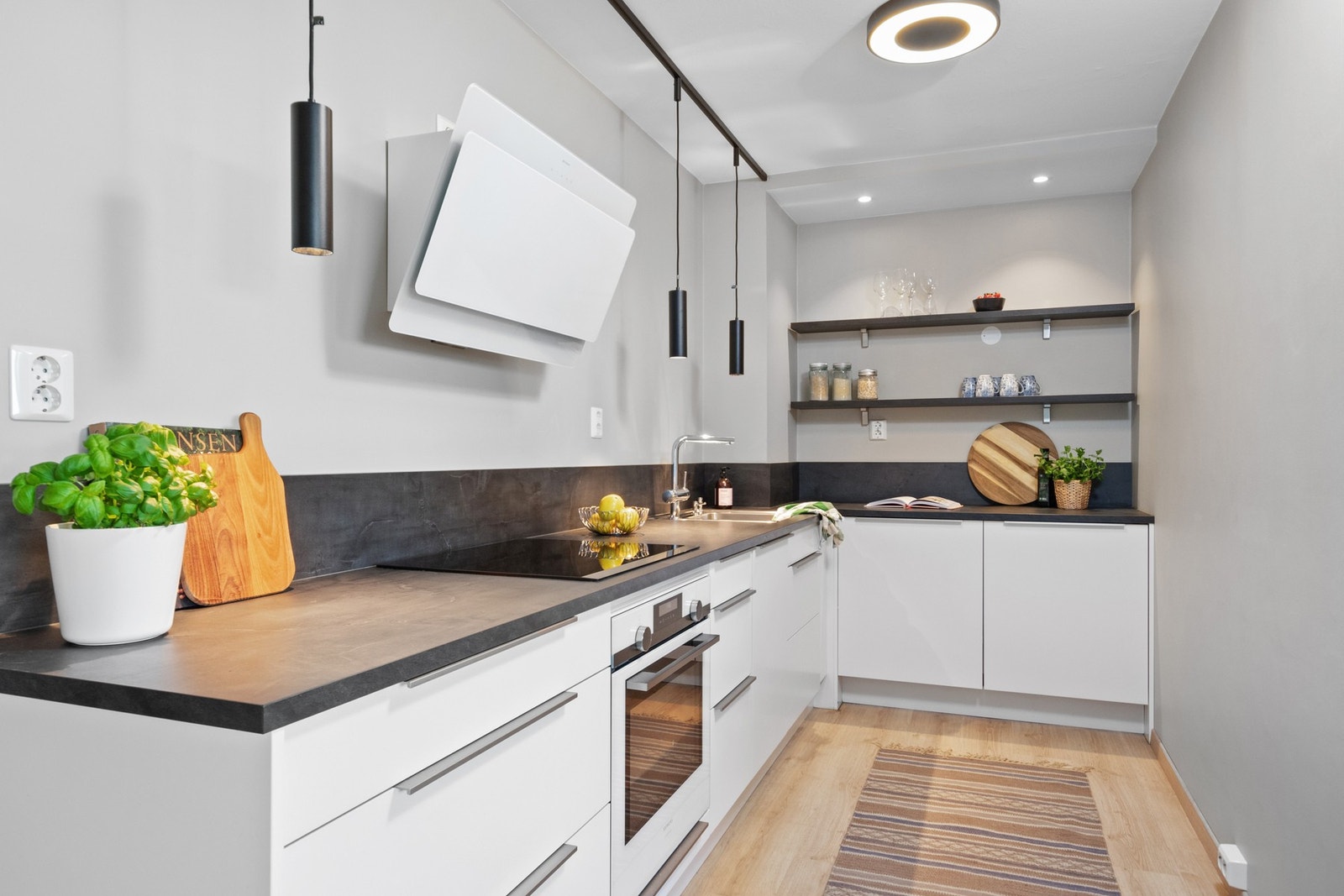 Innredningen har lyse, glatte fronter, god skap- og benkeplass, samt en sort hylleløsning i enden av kjøkkenet. Galleribilde