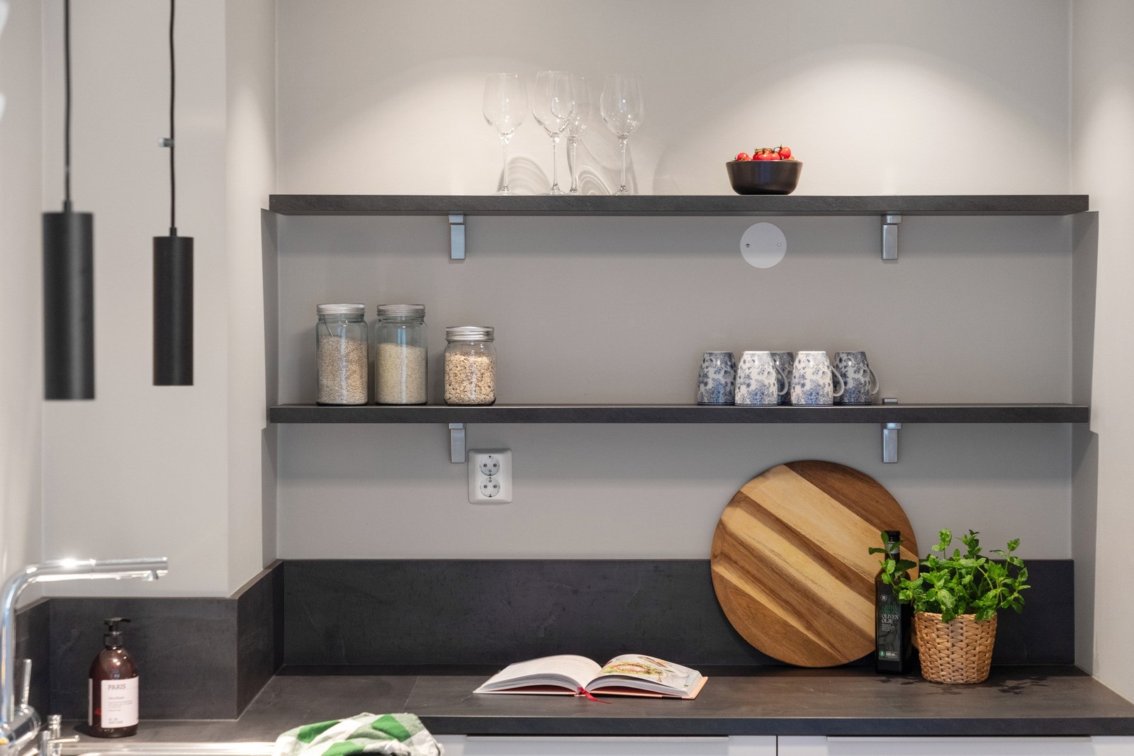 Benkeplaten er i sort laminat, og samme finish er brukt på veggen over benkeplaten for sprutbeskyttelse og enklere renhold. Galleribilde