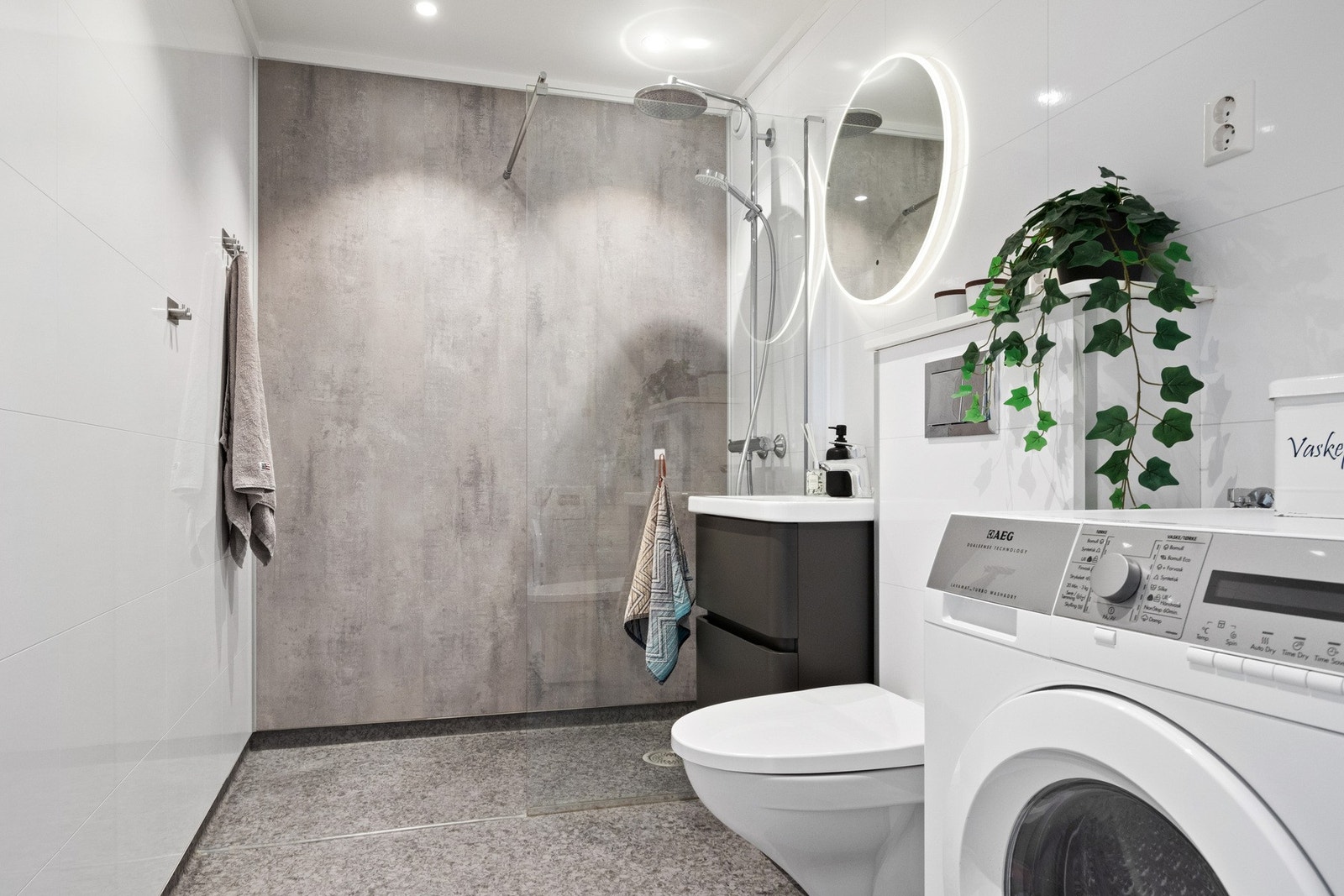 Badet er lyst og delikat og ble oppusset i 2020, med moderne, lyse flisplater på veggene, gråspettet vinylbelegg på gulvet, og hvitmalt himling med downlights. Galleribilde