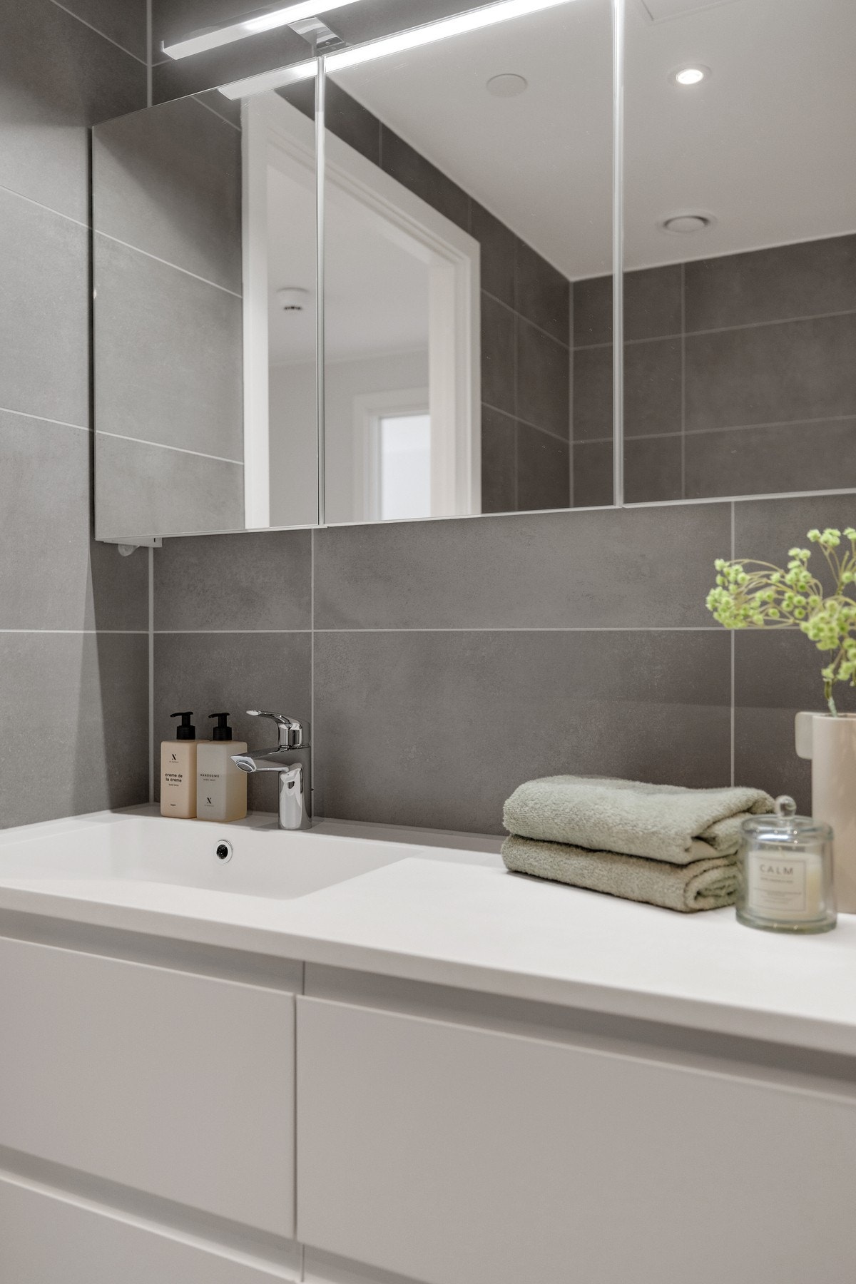 Baderomsinnredningen er bestående av servant med skuffeseksjon, speilskap med overlys, vegghengt klosett og dusjhjørne med svingbare glassdører. Galleribilde