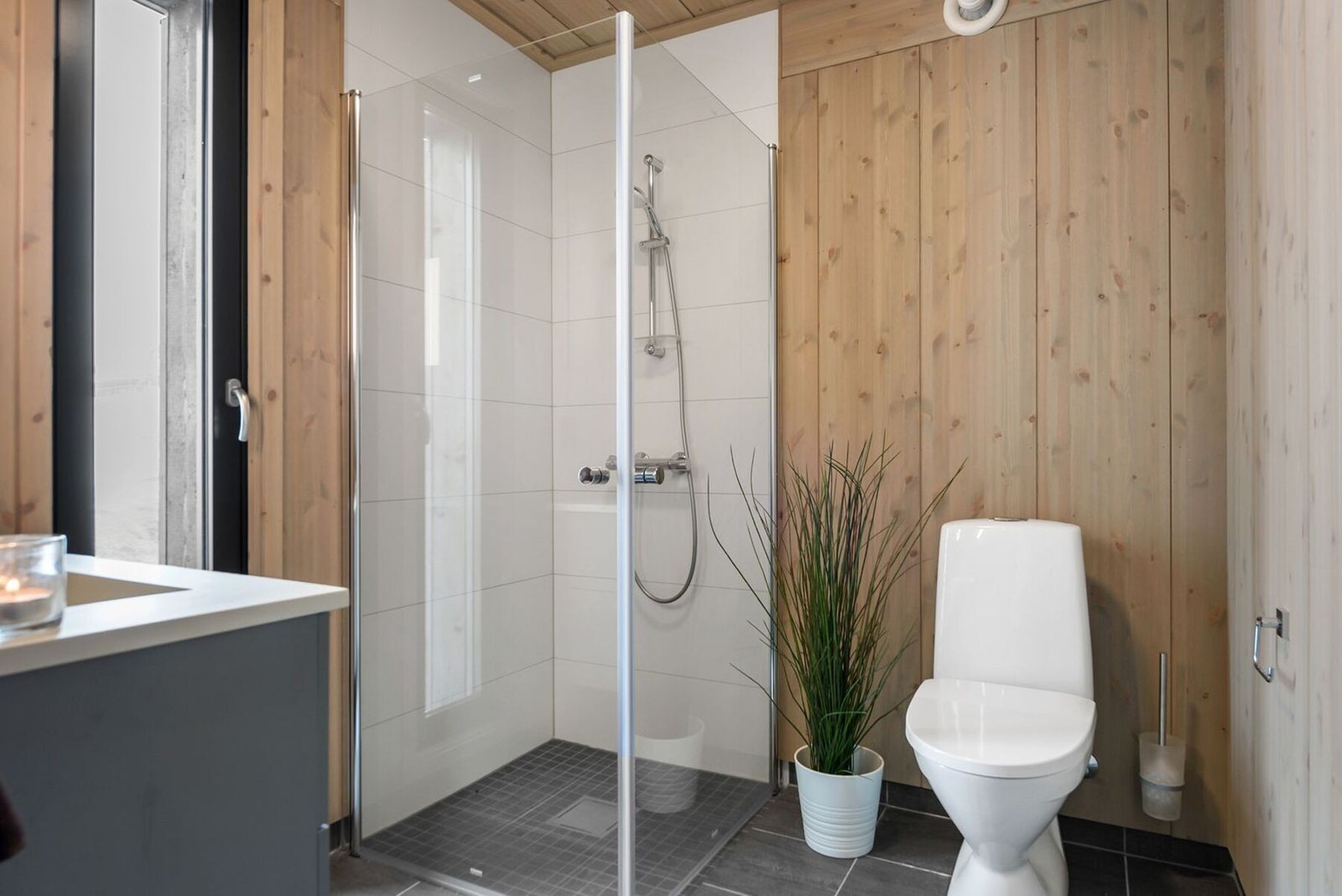 Flislagt gulv med varmekabler, flislagt dusjnisje og heltre Vy-panel på vegger. Foto fra visningshytte i Kjoslia Galleribilde