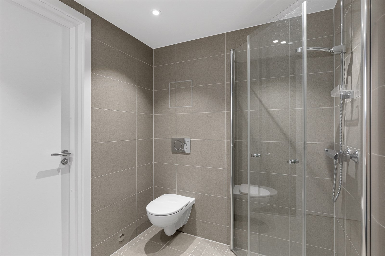 Baderommet har vegghengt toalett, dusjhjørne med dører i herdet glass. Galleribilde