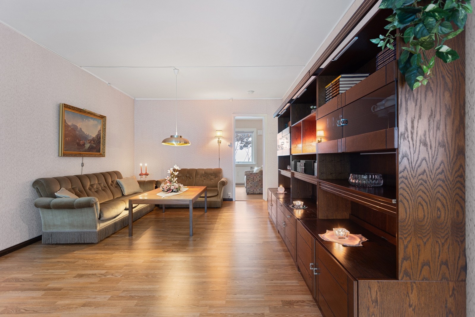 Rommet er innredet med en stor bokhylle i mørkt treverk og en sittegruppe Galleribilde