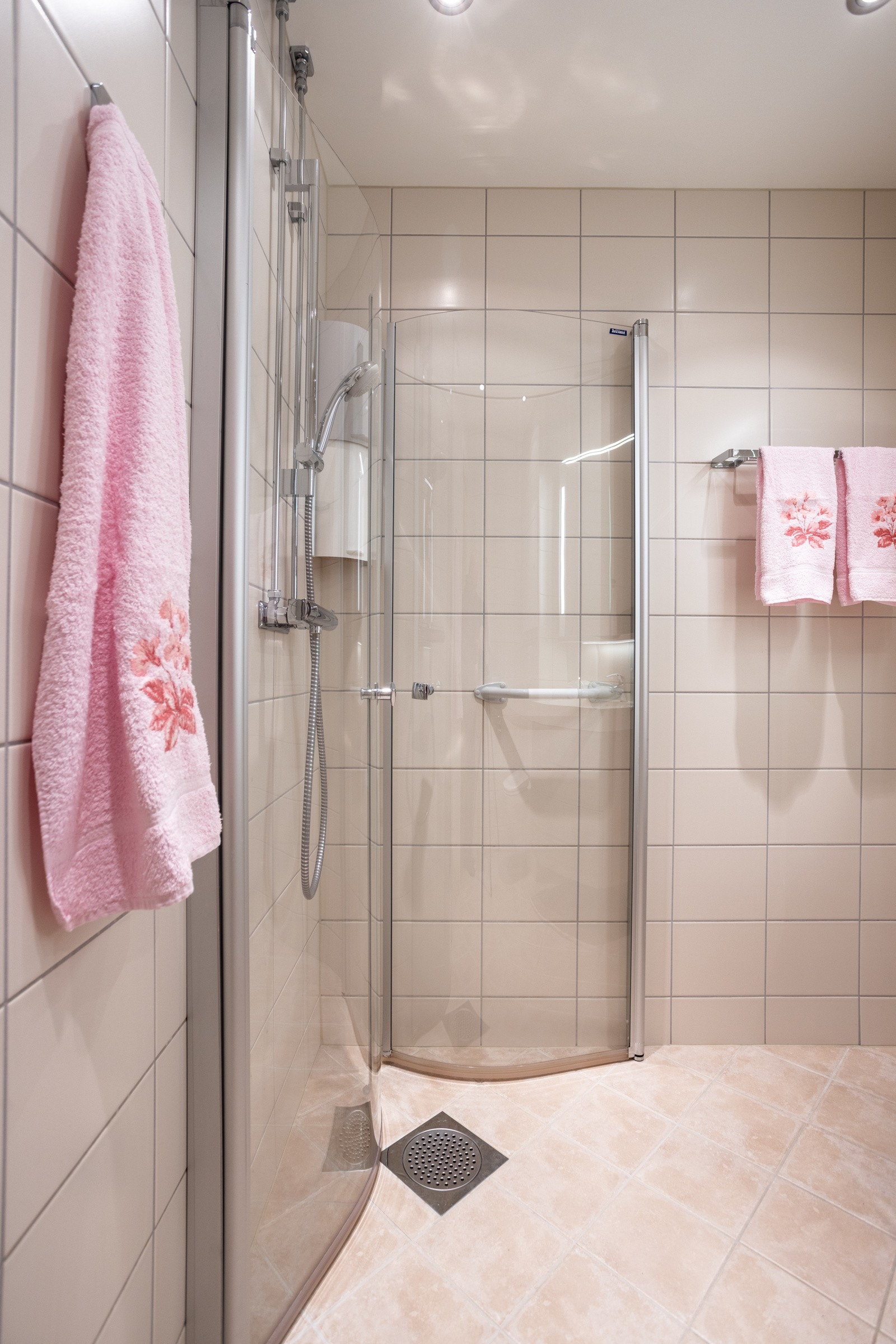 Badets innredning består av vegghengt toalett, servant med slette fronter, dusj med glassdører og opplegg for vaskemaskin Galleribilde