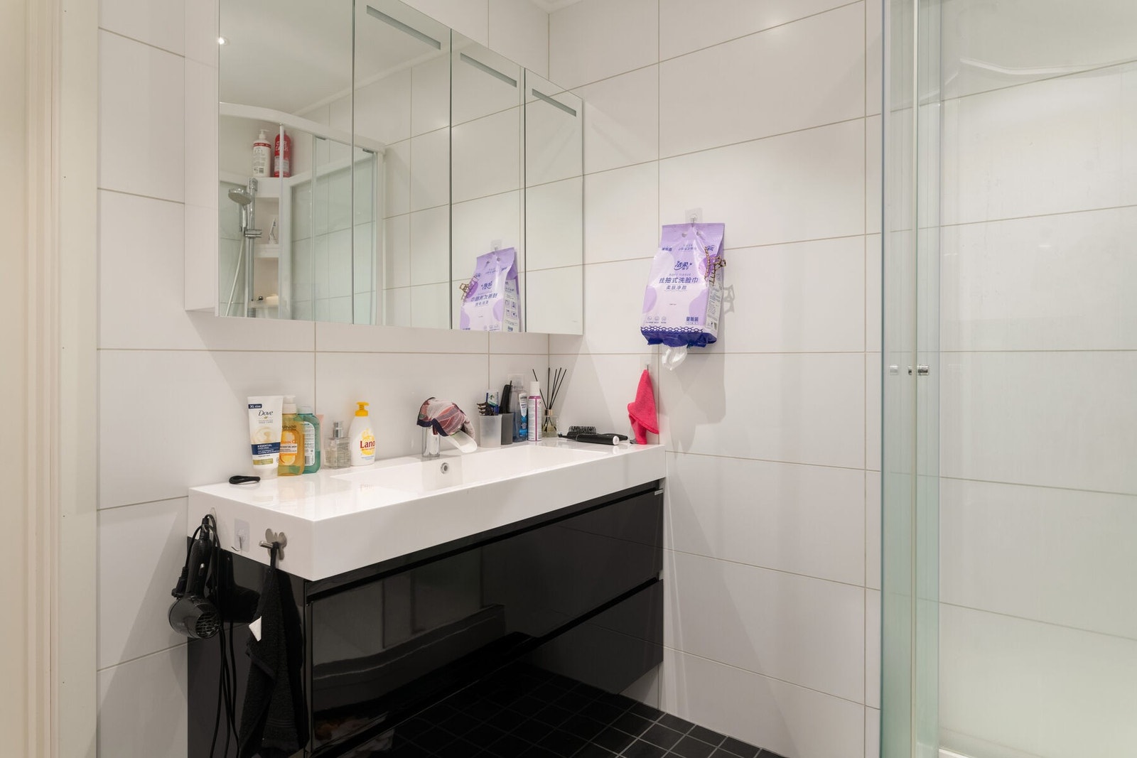 Badet har servant på skuffeseksjon, speilskap med belysning, dusjkabinett og veggmontert toalett. Galleribilde