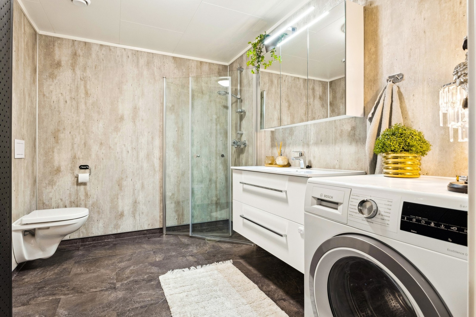 Det er et pent vinylbelegg på gulv med elektriske varmekabler, innfellbart dusjhjørne, toalett, fine overflater og opplegg for vaskemaskin. Galleribilde