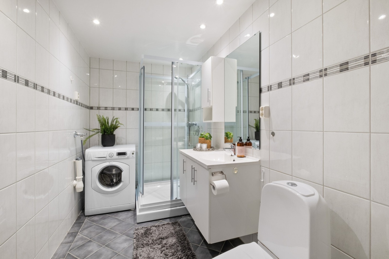 Flislagt bad med dusjkabinett nytt i 2023, gulvmontert toalett og opplegg for vaskemaskin. Galleribilde