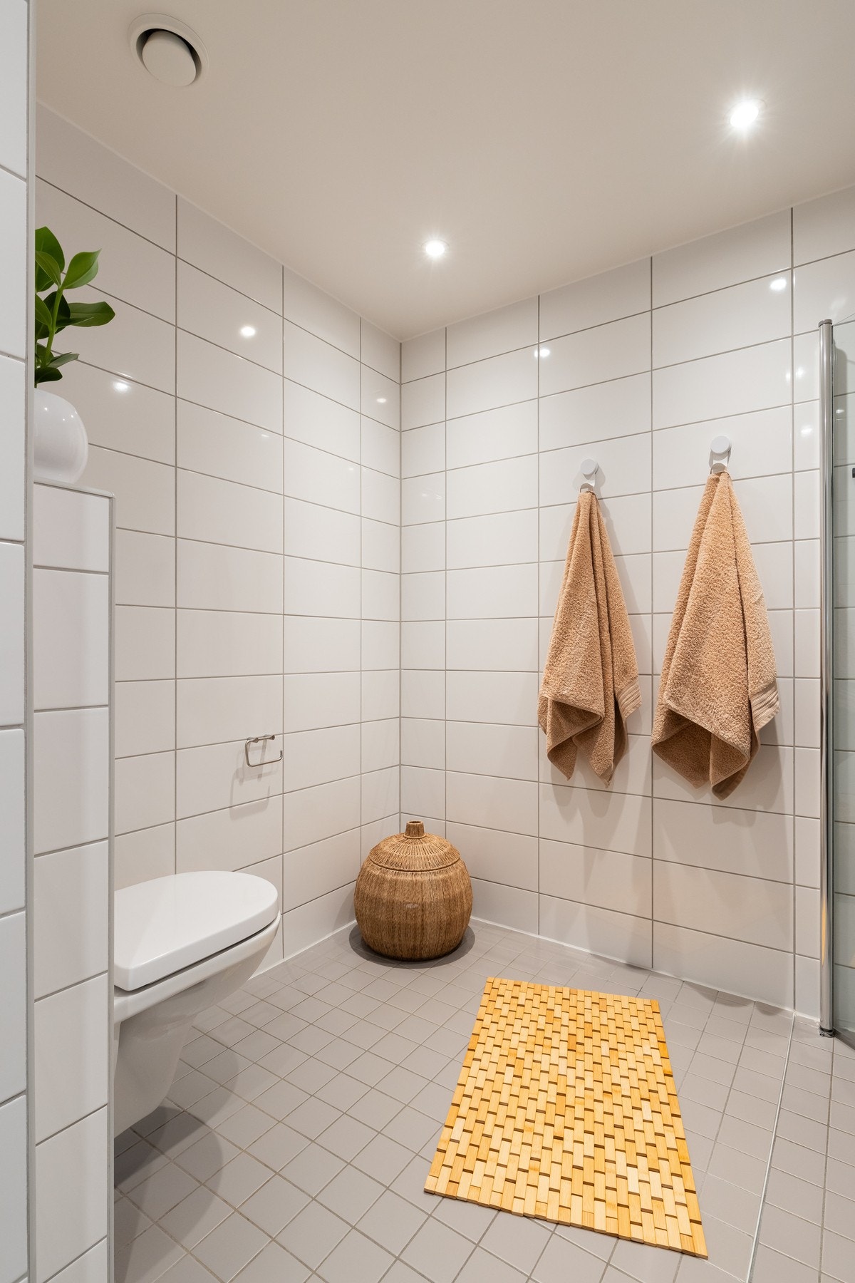 Videre er det dusjhjørne med innfellbare glassdører som frigjør plass på gulvet. Badets utforming og romslige størrelse gir mulighet for å sette inn badekar om ønskelig. Galleribilde