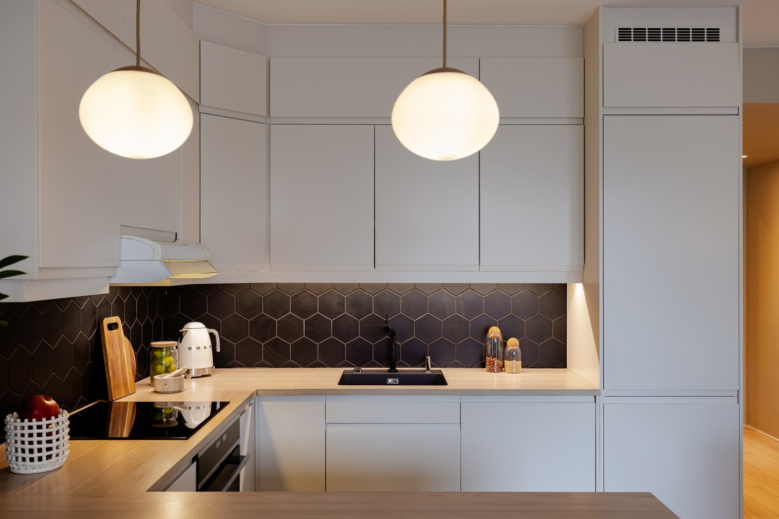 Sort nedsenket oppvaskkum og integrerte hvitevarer som induksjonstopp, kjøl-/fryseskap fra 2024, komfyr med ventilator over og oppvaskmaskin. Galleribilde