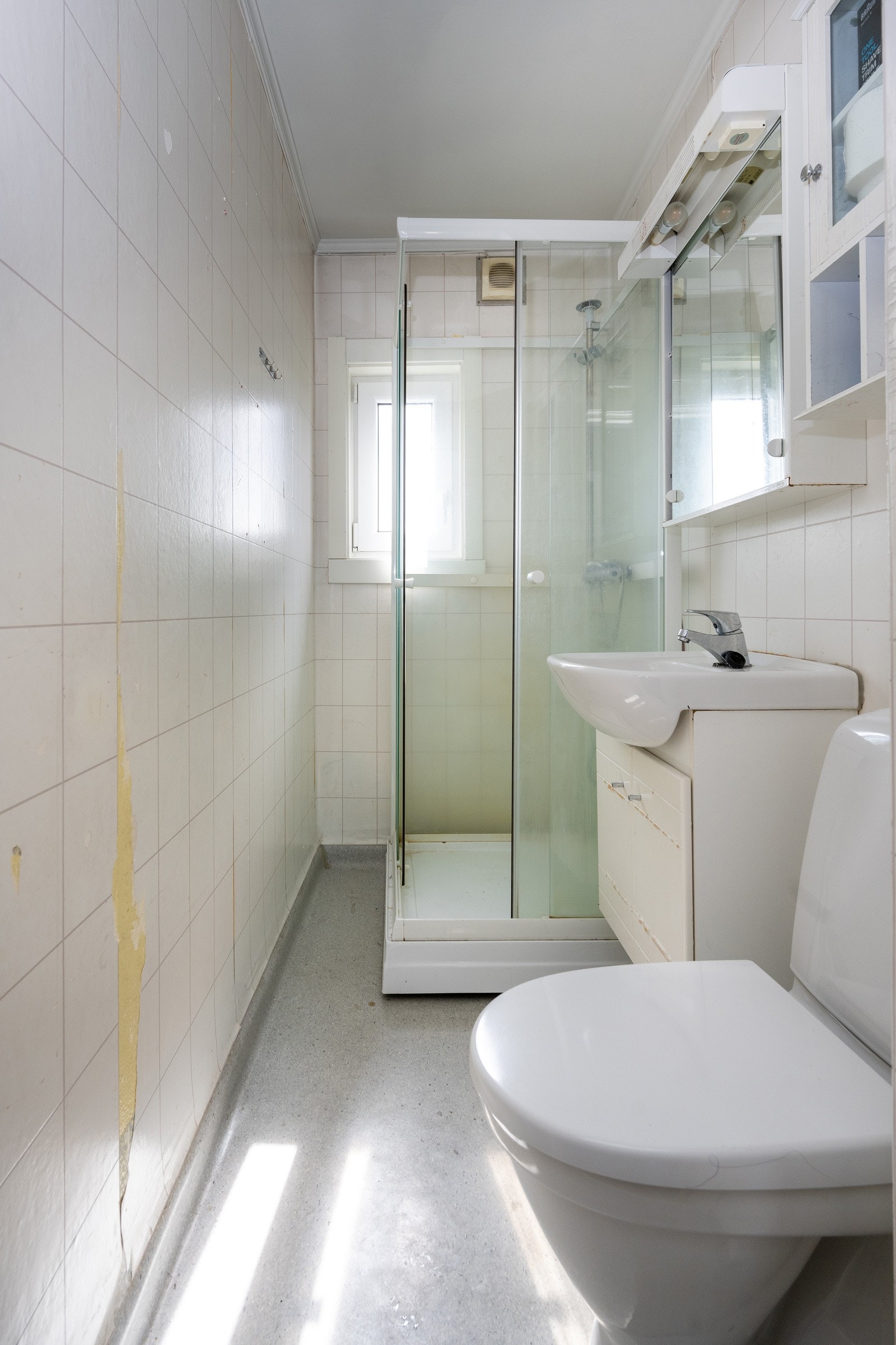 Lyst bad med vegghengt servant med profilerte fronter, speil, dusjkabinett og toalett. Galleribilde