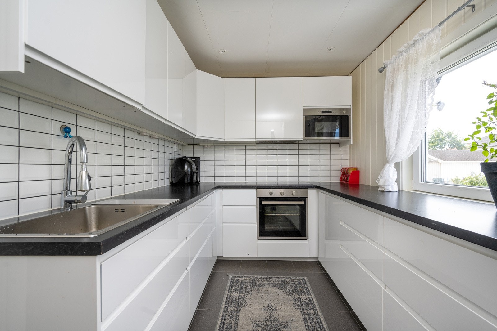 Hvit kjøkkeninnredning med glatte fronter fra 2018 og sort benkeplate. Galleribilde