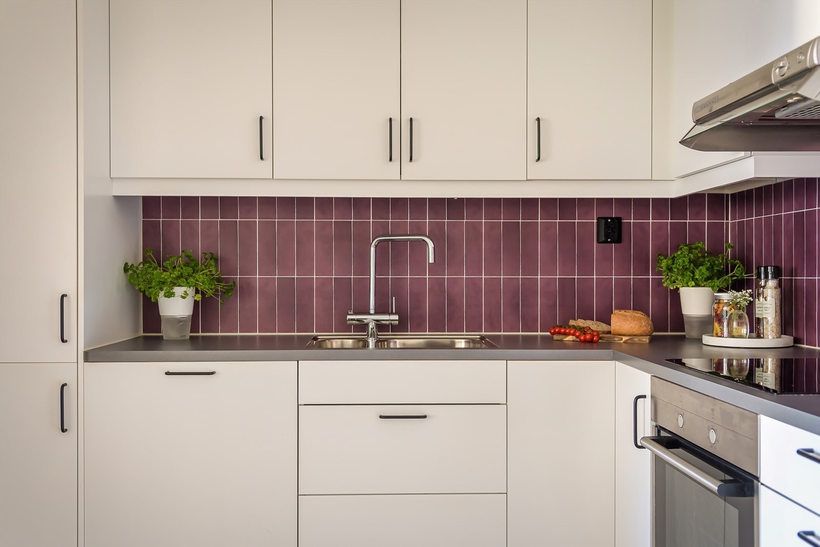 Kjøkkeninnredningen har hvite fronter, fliser på bakveggen og en laminert benkeplate. Galleribilde