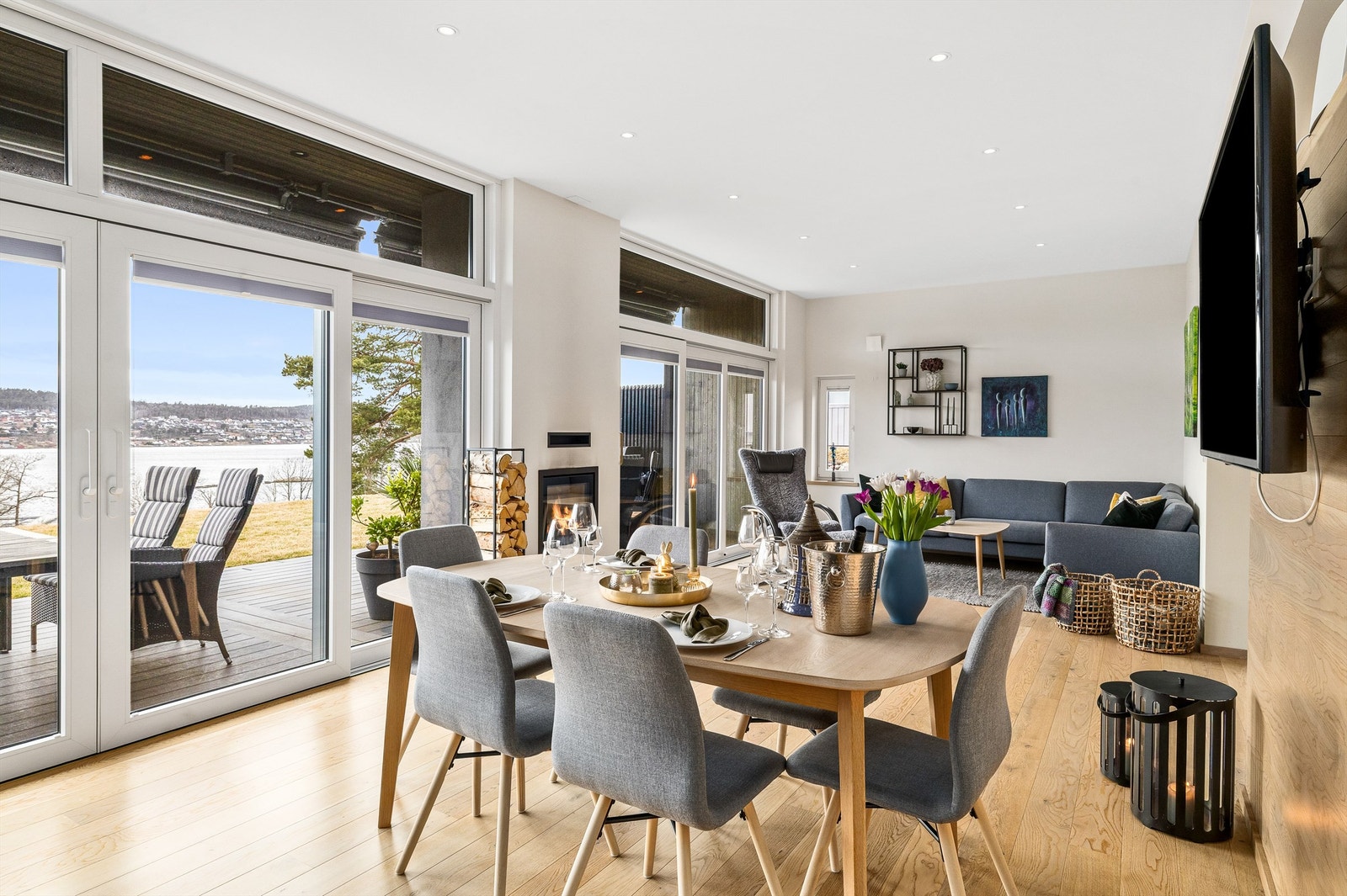 ÅPNER OPP MED GLASSVEGG. Ytterveggen mot sjøen i allrommet med to glassdører, gjør det mulig å dekke langbord som kan stå både inne i stuen og ute på terrassen. Nivået på gulvet er likt og skillet mellom inne og ute viskes ut. Galleribilde