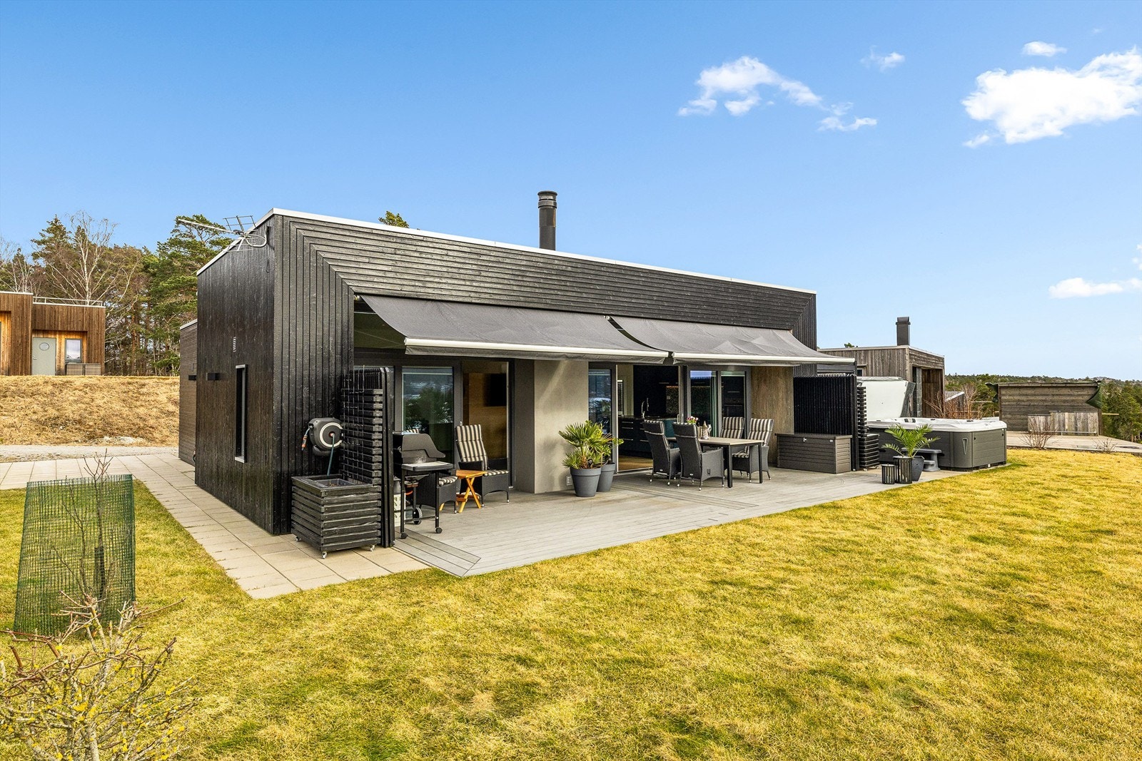 Store terrassemarkiser med elektrisk styring gir skygge på solfylte dager på terrassen. Galleribilde