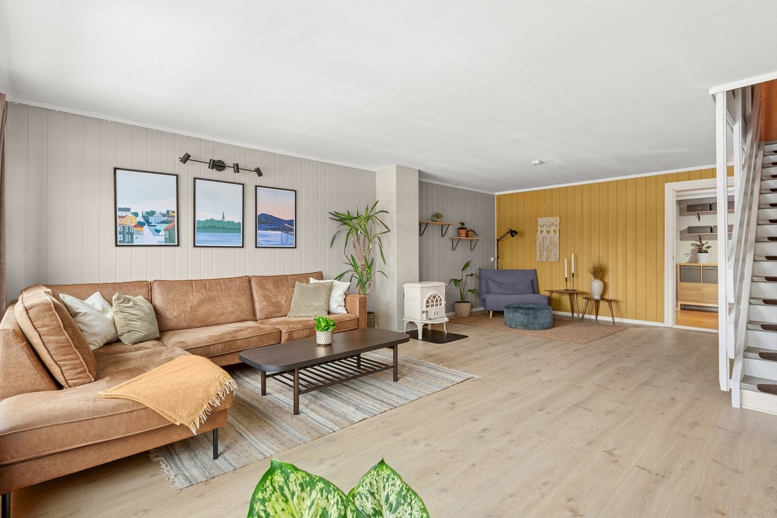 Stua har flere møbleringsalternativer, men deles naturlig inn i to soner med en vedovn. Galleribilde
