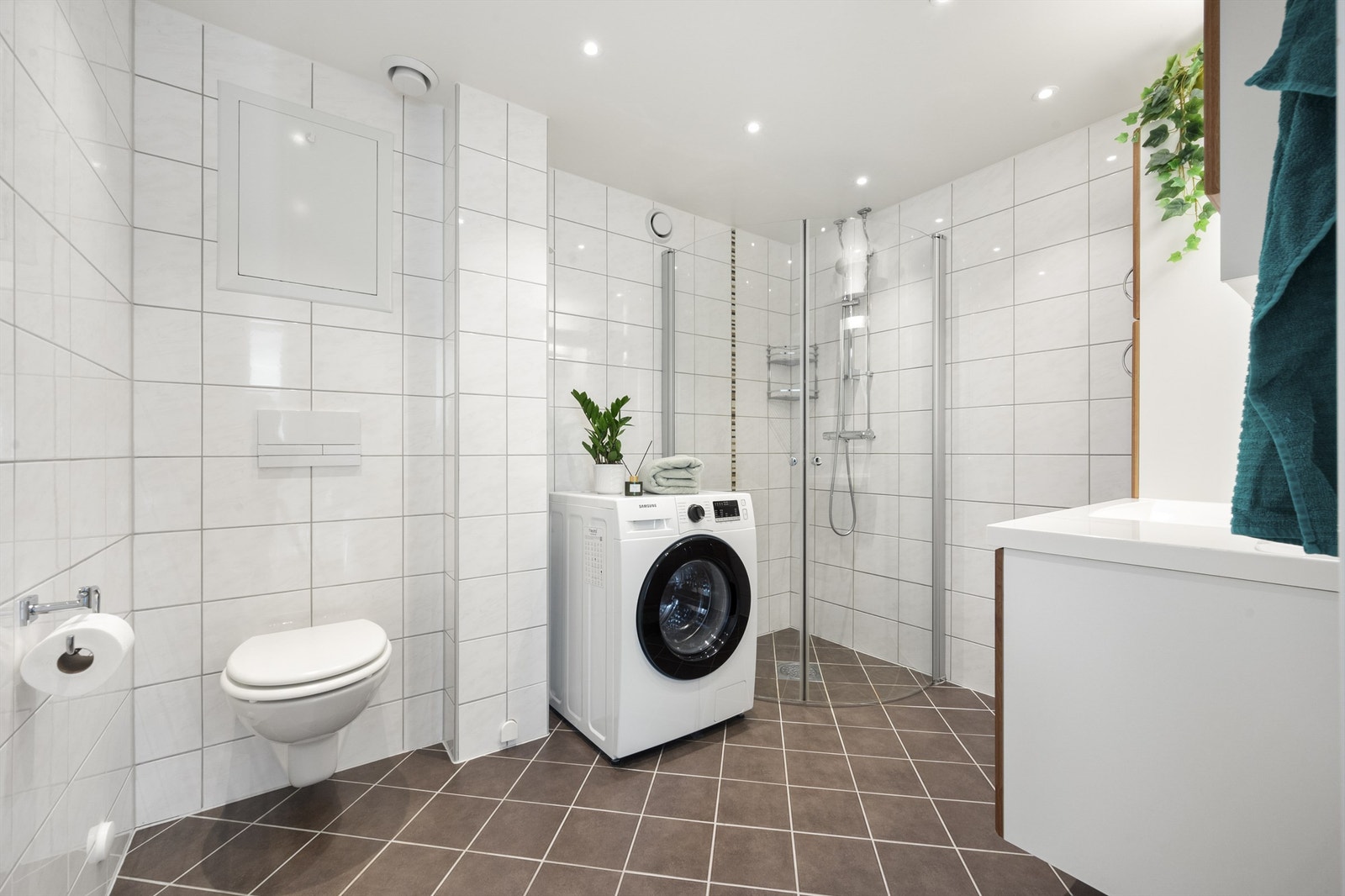 Videre har badet dusjhjørne med glassdører og vegghengt toalett med innebygget sisterne. Det er opplegg for vaskemaskin. Galleribilde