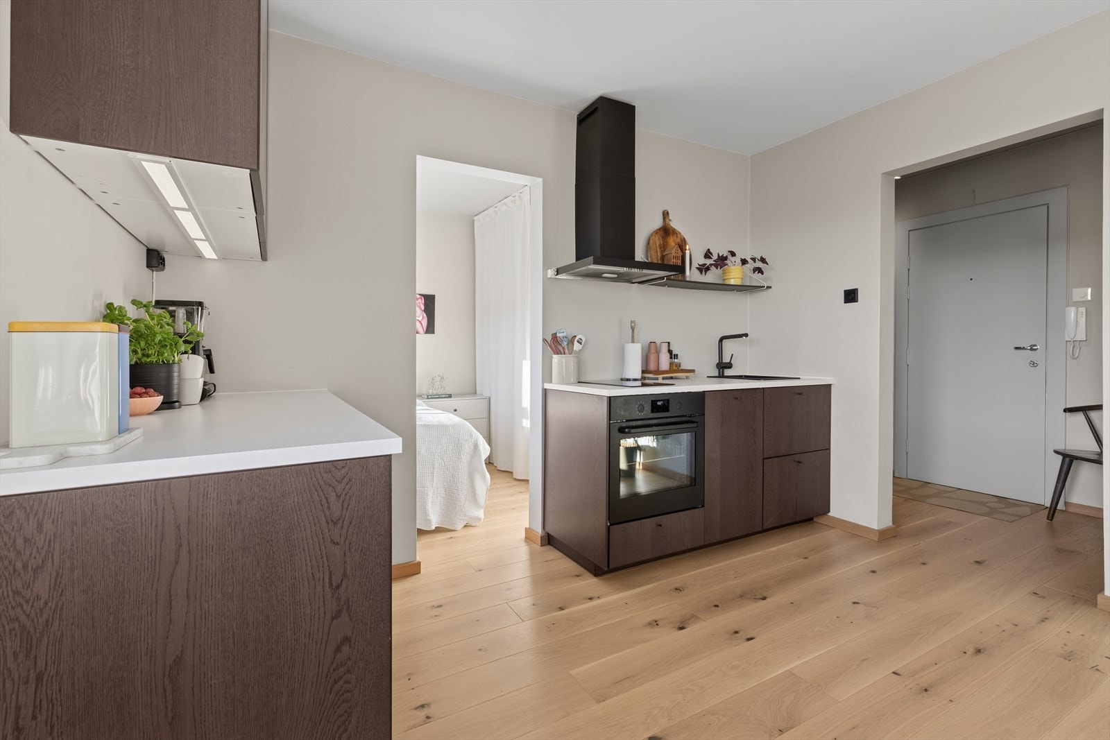 Kjøkkeninnredning med mørke glatte fronter, laminert benk, integrert oppvaskmaskin, kjøleskap under benk, koketopp og stekeovn. Galleribilde