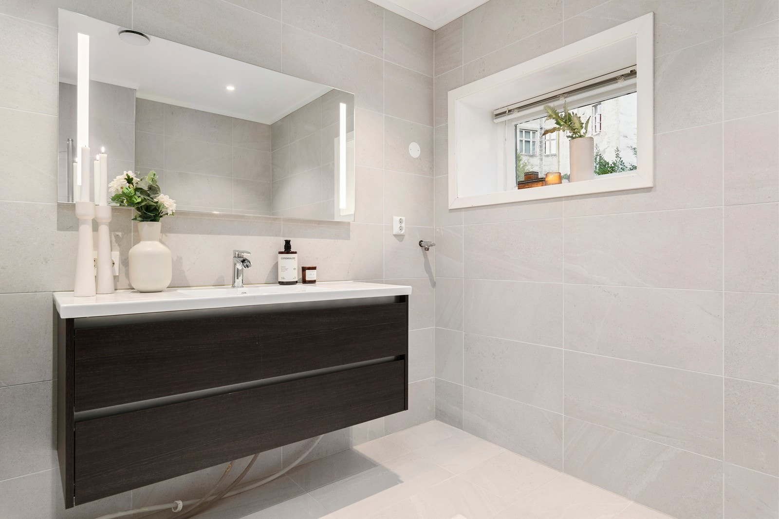 Badet er innredet med baderomsinnredning, speil med integrert belysning - Galleribilde