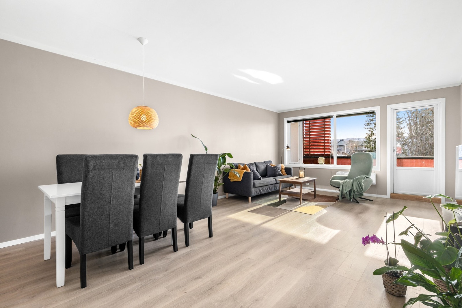 Lys og romslig stue med laminat på gulv og malte, slette flater på vegger og i himling Galleribilde