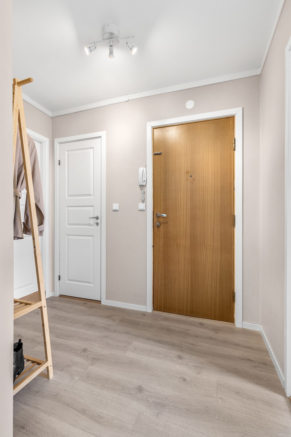 Romslig entré med laminat på gulv og slette vegger malt i en lys beige farge Galleribilde
