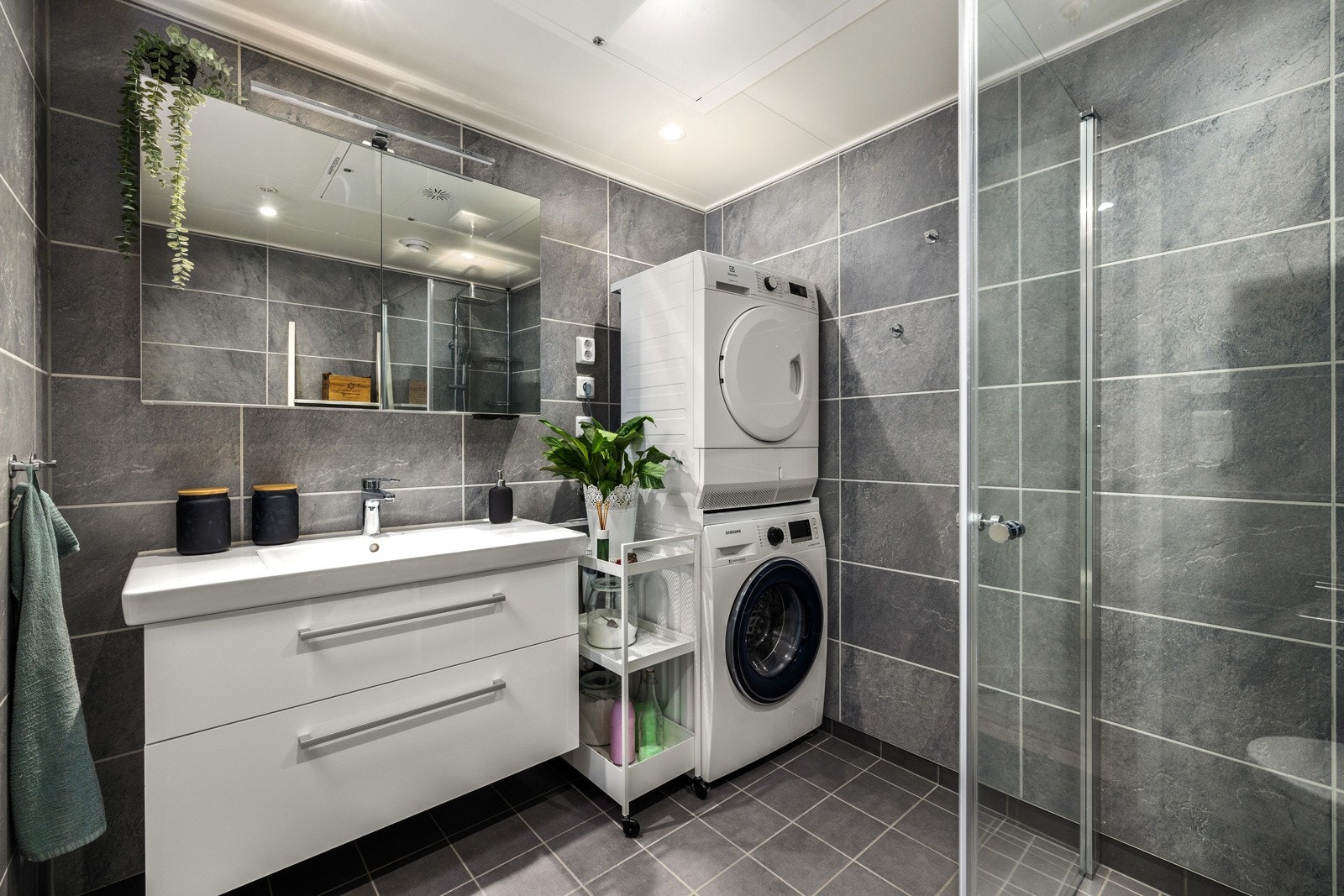 Badet er innredet med dusjhjørne, vegghengt toalett, servantinnredning og opplegg for vaskemaskin. Galleribilde