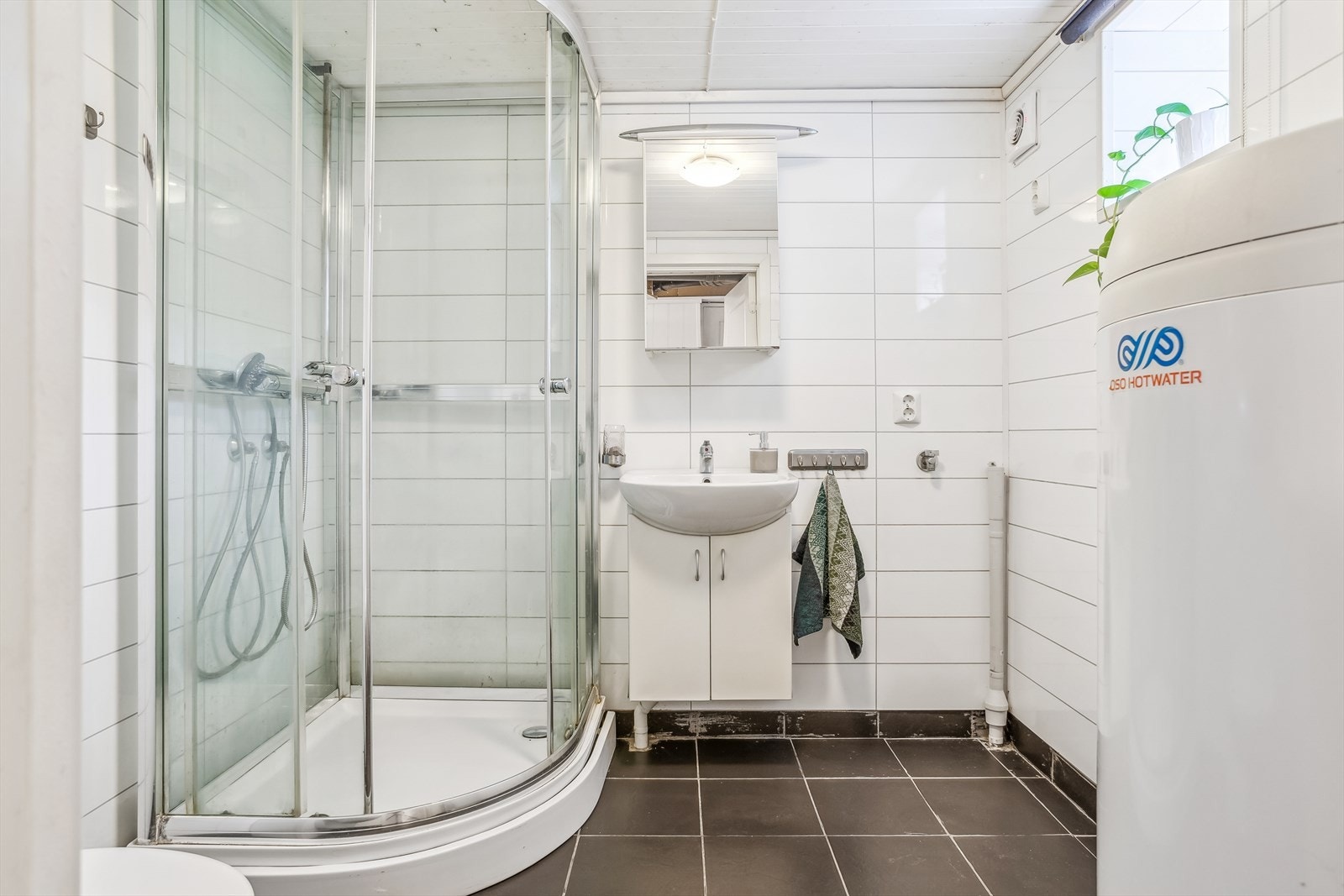 Bad med gulvfliser, servant m/skapinnredning, kabinett og toalett. Det er opplegg til vaskemaskin Galleribilde