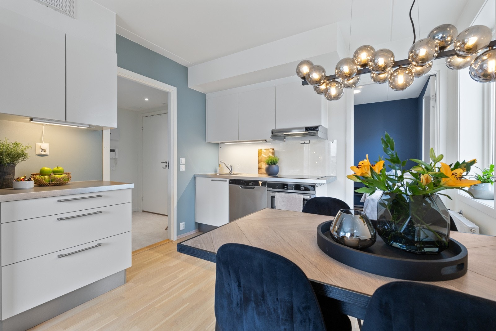 Stilrent kjøkken fra Sigdal i åpen løsning. Innredningen består av hvite slette fronter og laminert benkeplate med nedfelt vaskekum i rustfritt stål. Galleribilde