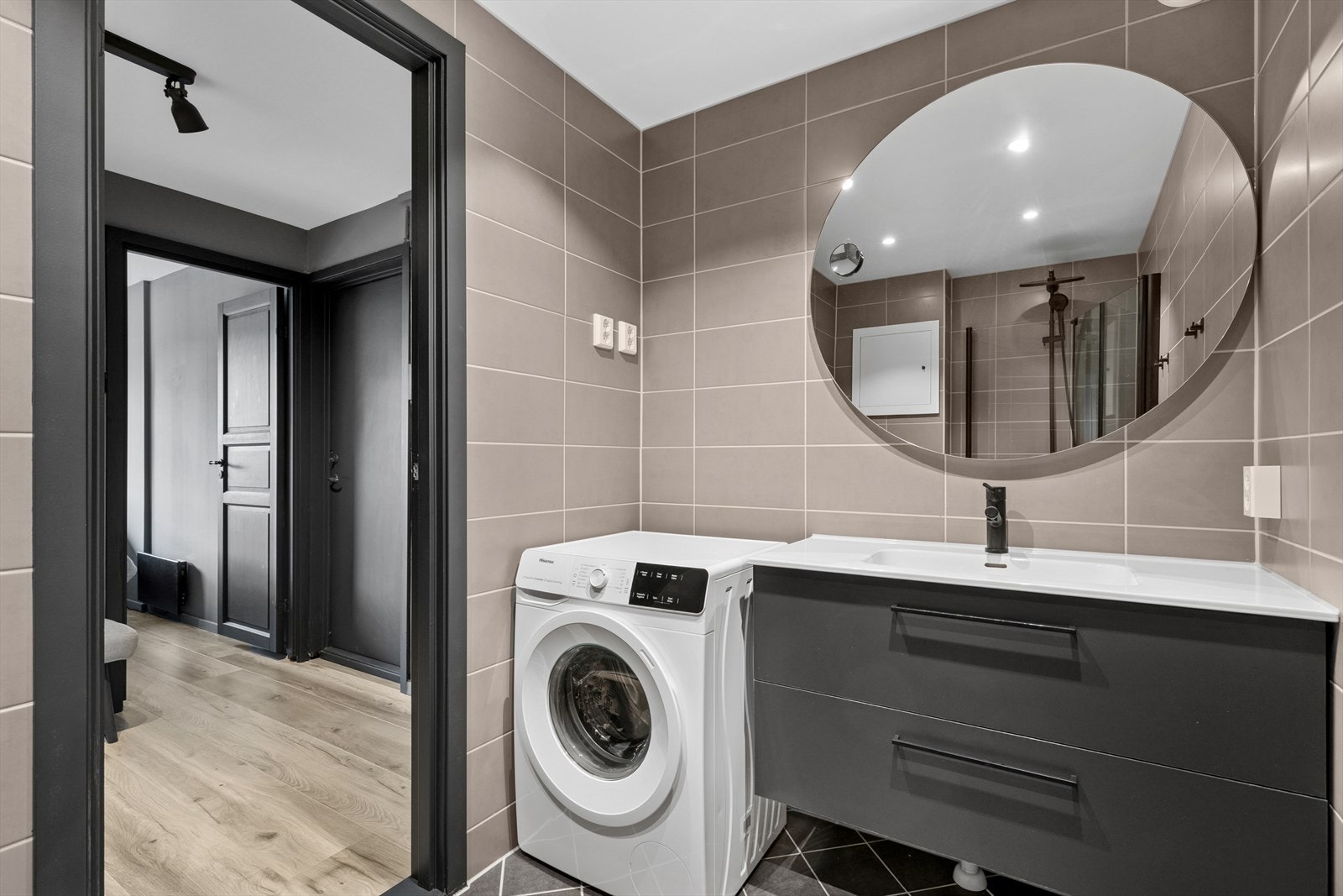 Badet er utstyrt med et vegghengt toalett, en servant med skuffer, et stort speil og en dusj med svingbare glassdører. Det er også tilrettelagt for vaskemaskin. Galleribilde