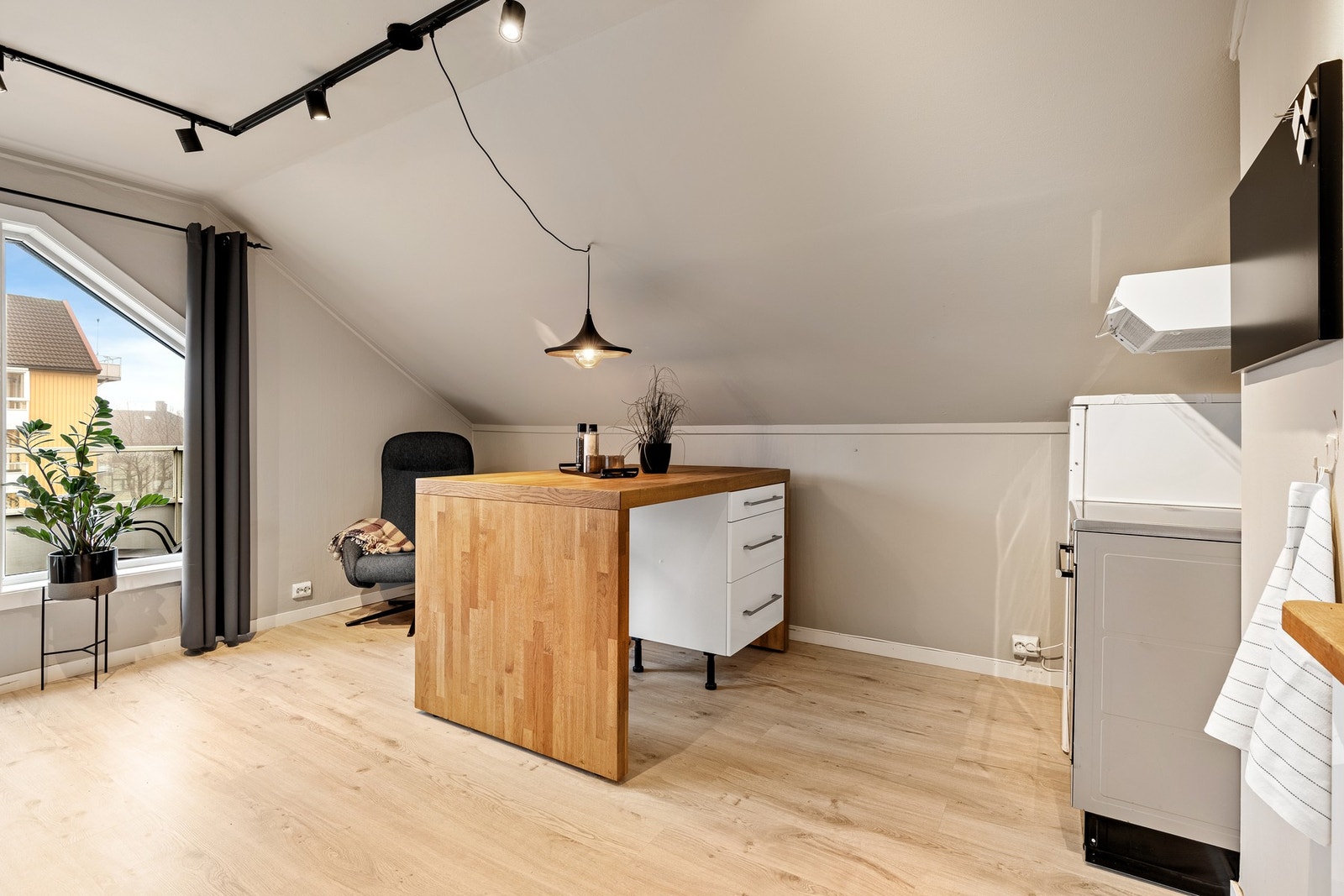 Lys loftsleilighet med skråtak. Store vinduer slipper inn naturlig lys. Åpen kjøkkenløsning med benkeplate i tre. Lyse vegger og gulv gir en romslig følelse. Galleribilde