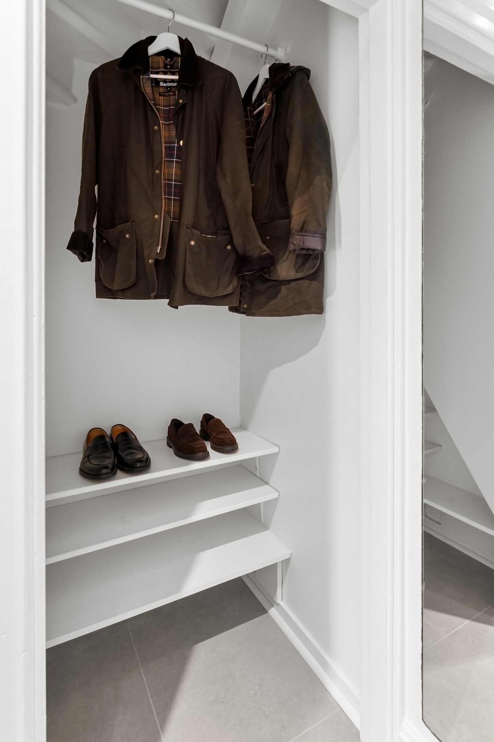 Plassbygd garderobe under trapp. Sjenerøs plass til sko og yttertøy gir hjemmet en følelse av organisert eleganse. Galleribilde