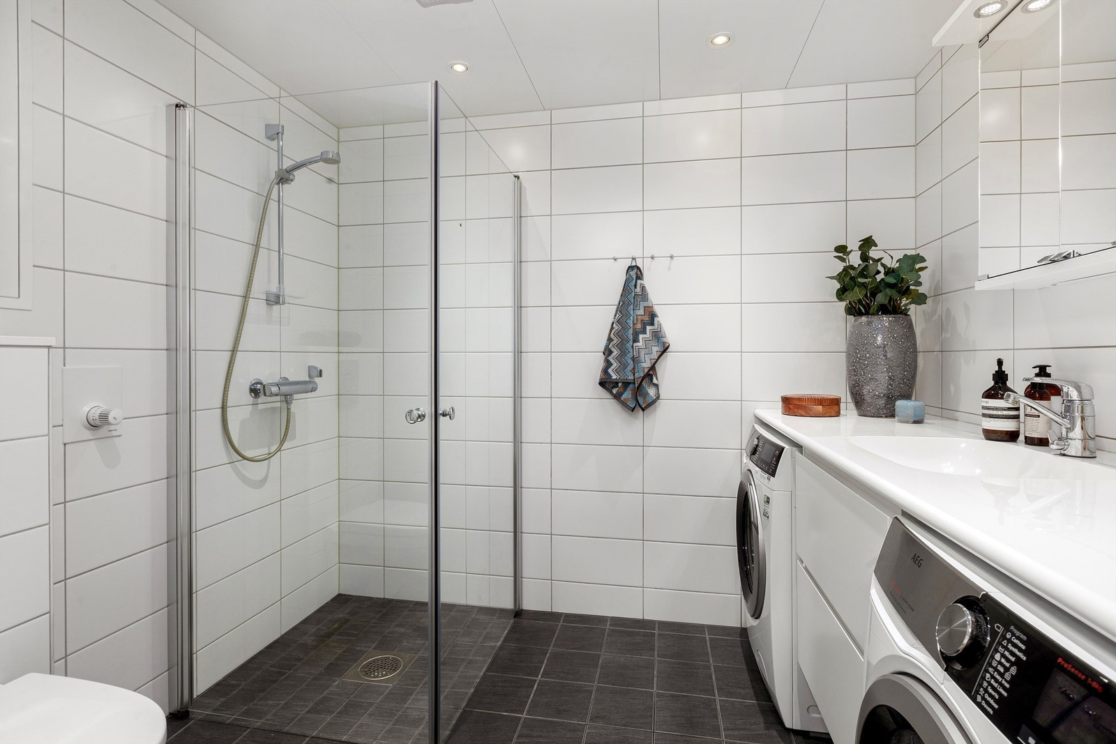 Bad - Dusjnisje med glassdører med ett-greps armatur. Vegghengt toalett med innebygd sisterne. Himlingsflate utført i himlingsplater med downlights. Galleribilde