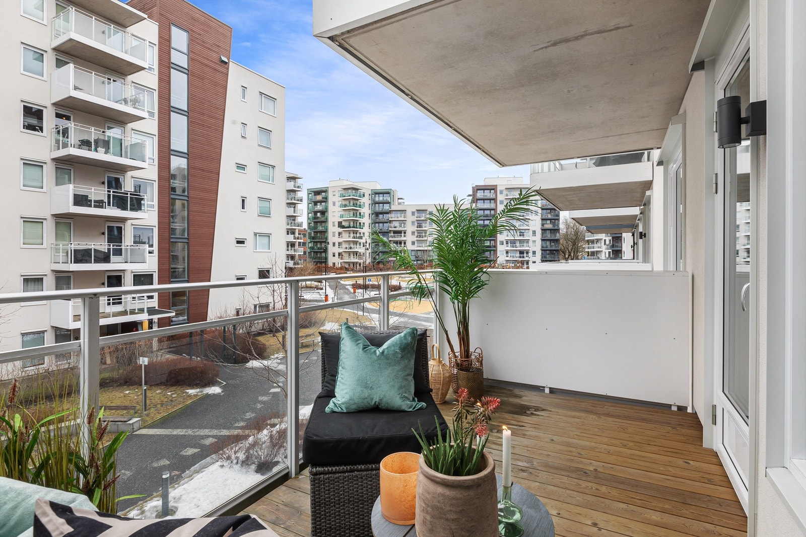 Vestvendt uteplass med utsikt over gårdstun. Gulv med terrassebord. Rekkverk i stål med innfelte glassplater. Belysning og stikkontakter. Galleribilde