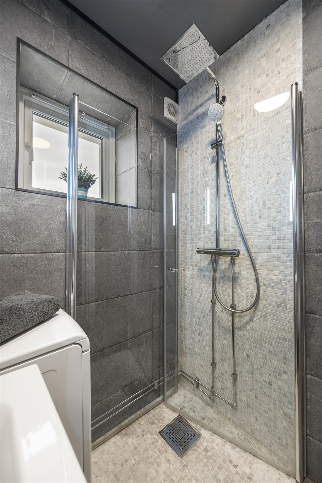 Badet er utstyrt med praktisk dusjhjørne med innfellbare dusjdører, servant med innredning, toalett og opplegg for vaskemaskin. Galleribilde