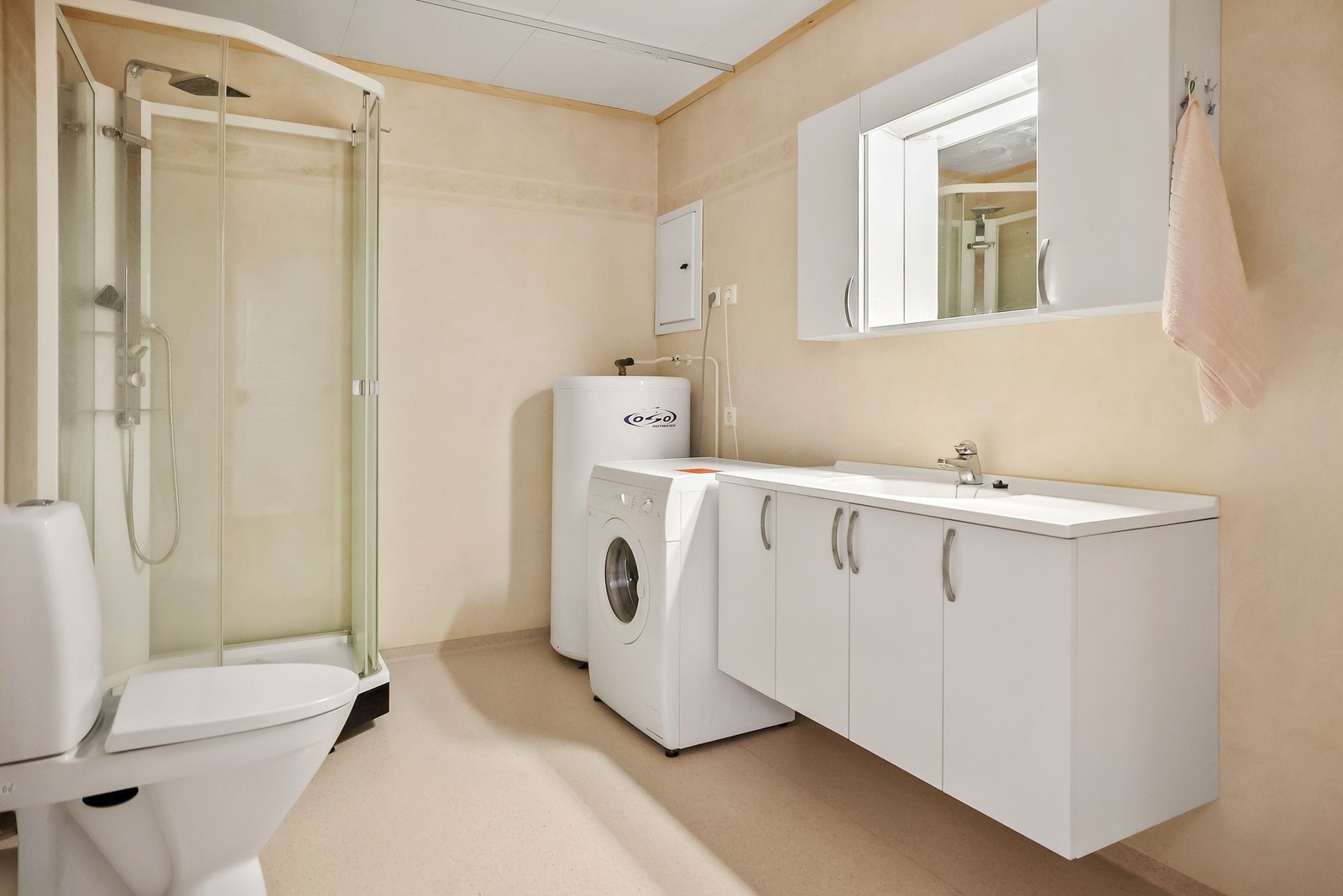Bad utstyrt med dusj, opplegg for vaskemaskin, og vegghengt innredning. Galleribilde