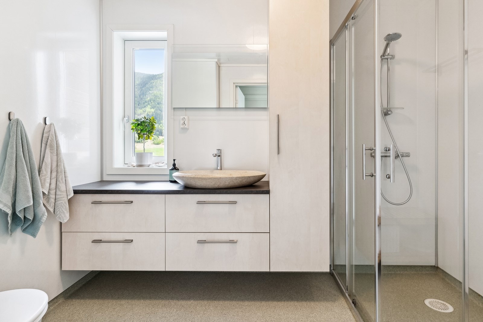 Bad i 1. etasje er innredet med nedfelt servant, veggmontert toalett og dusjhjørne. Galleribilde