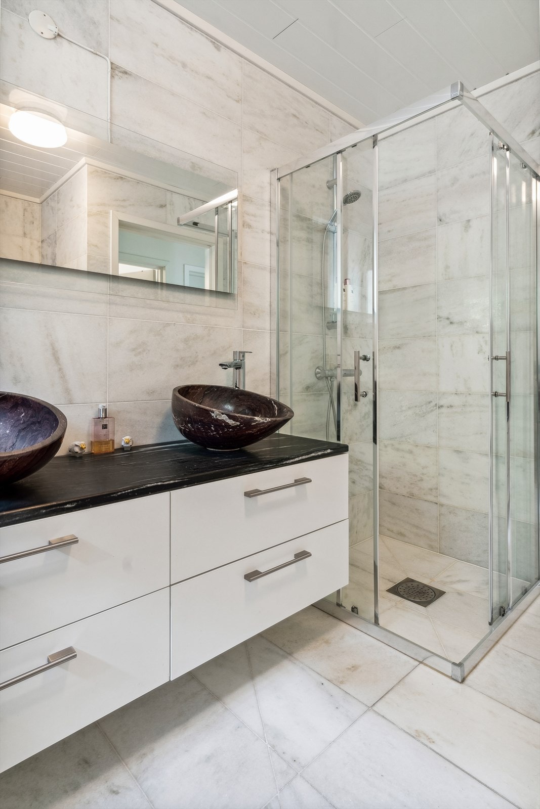 Badet er innredet med to servanter, veggmontert toalett, badekar og dusjhjørne. Galleribilde