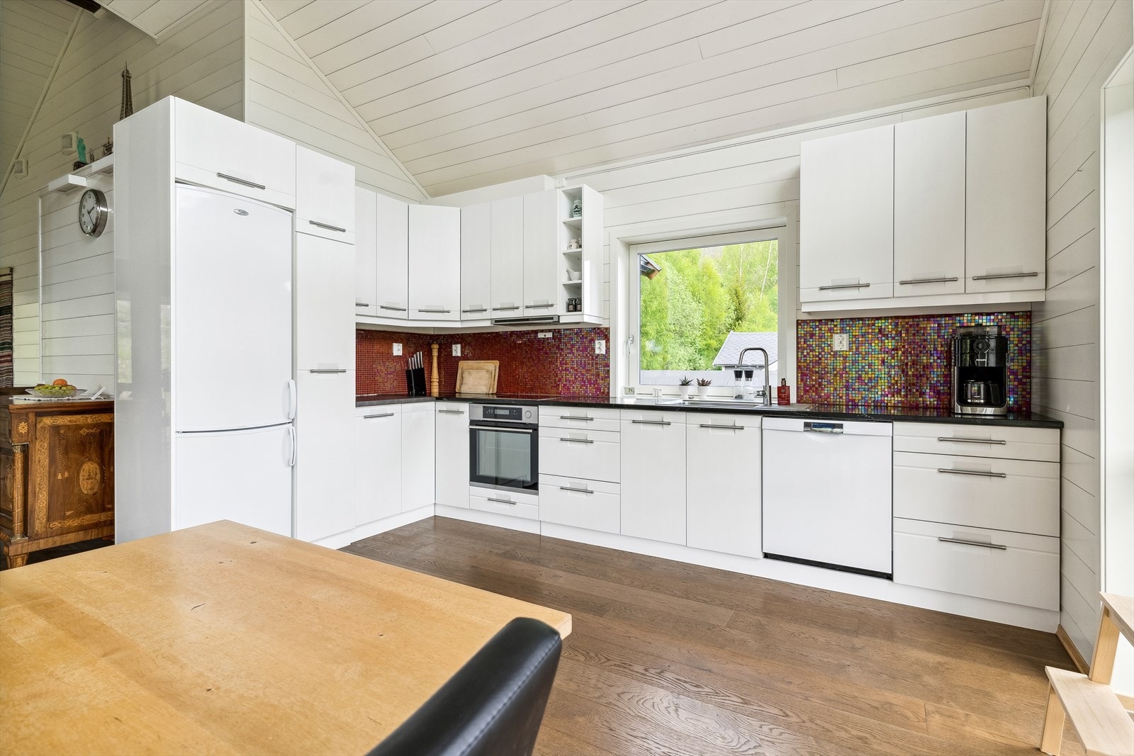 Fint kjøkken med benkeplate av stein og mosaikk mellom benkeplate og overskap. Galleribilde