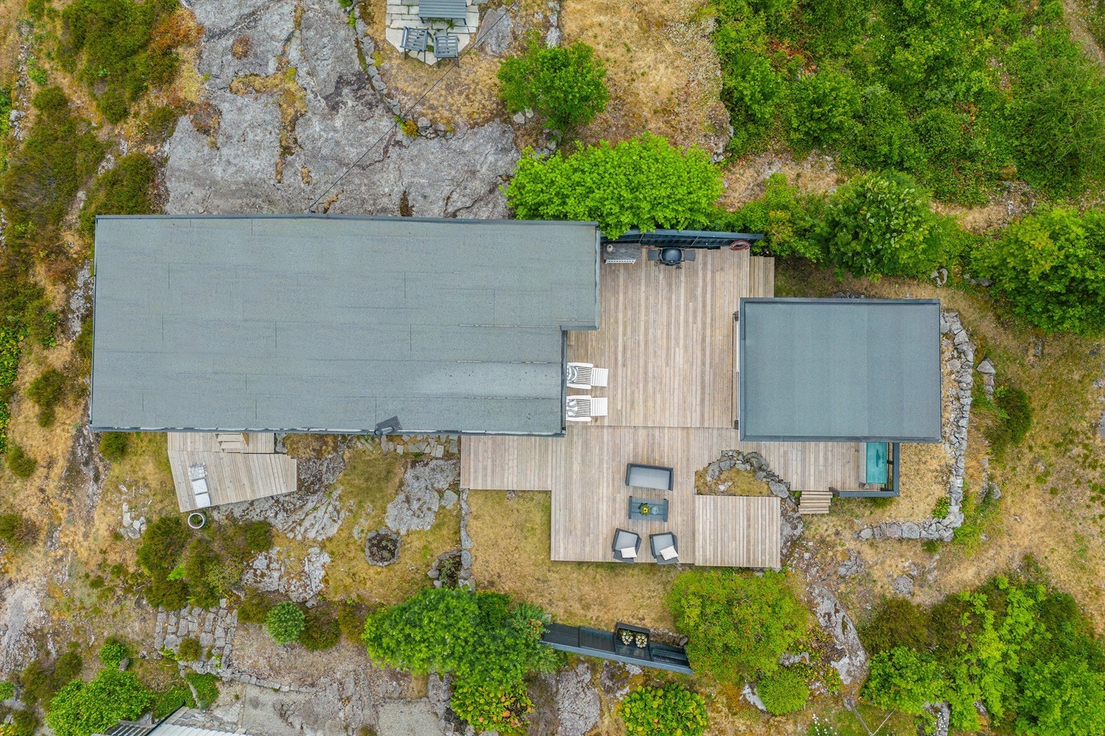 Store terrasseflater med ulike soner for utelounge, spiseplass og et enkelt utekjøkken. Galleribilde