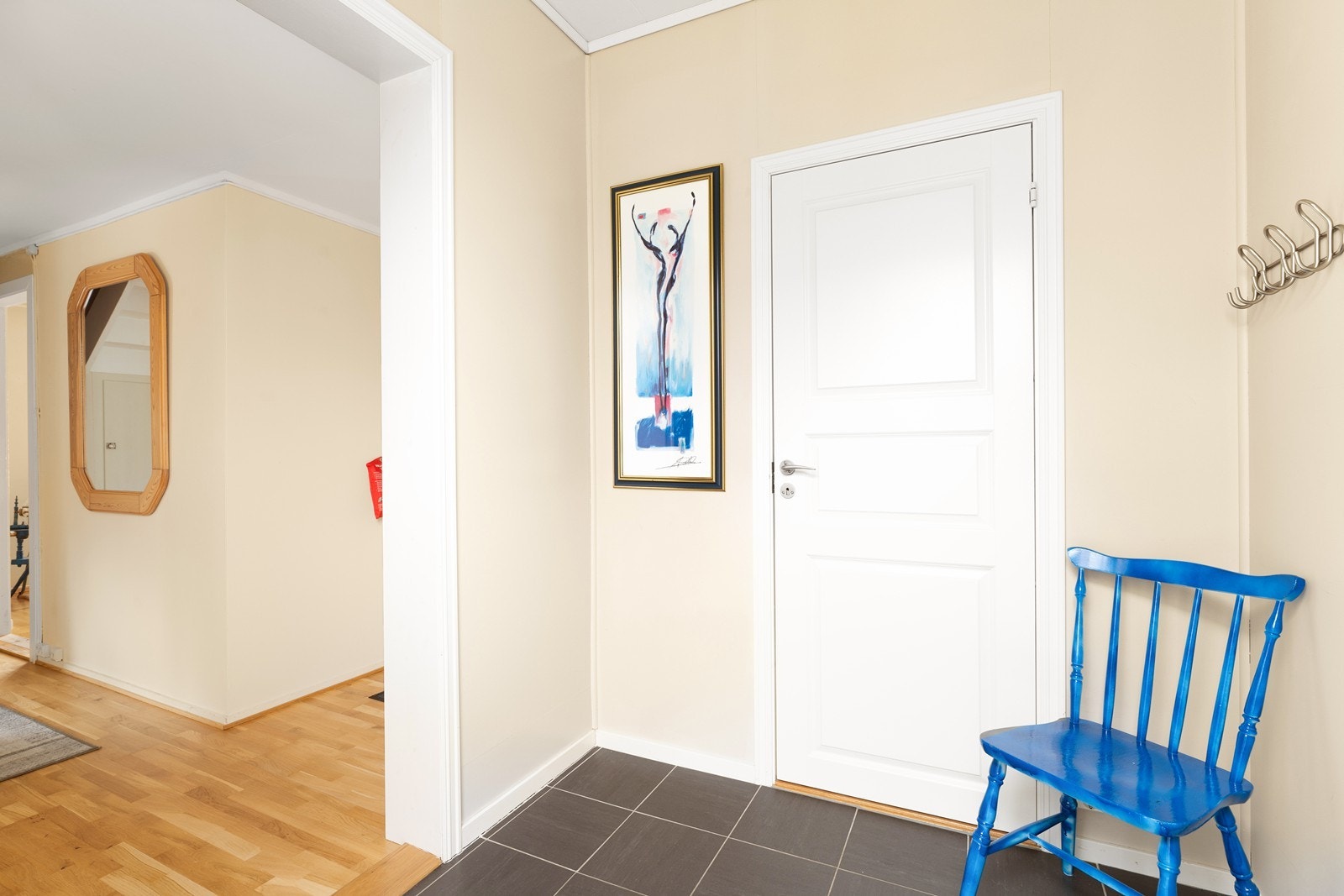 Fra et overbygget inngangsparti blir du ønsket velkommen inn i en pen, flislagt entré med plass til jakkeoppheng og skohylle Galleribilde