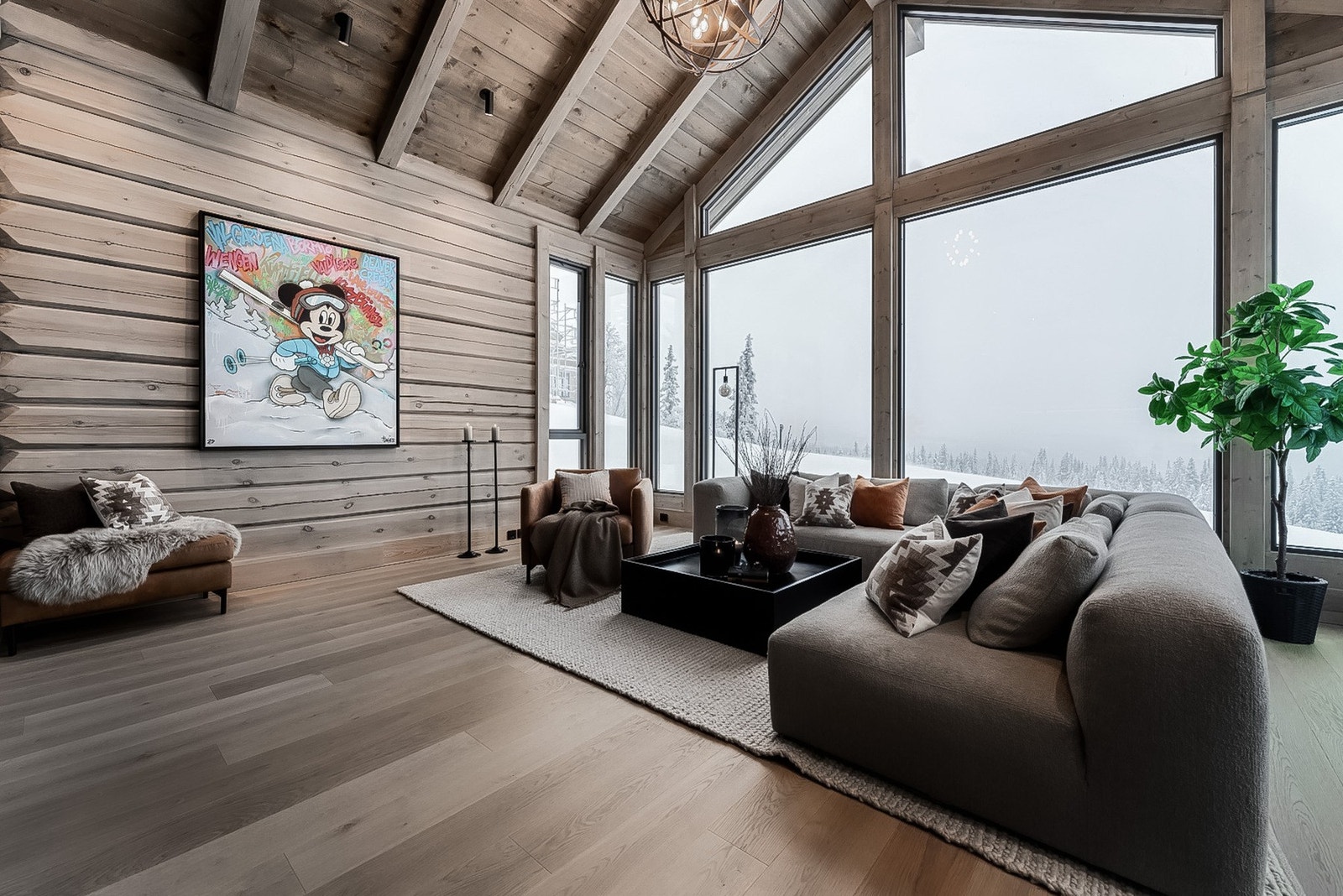 Romslig stue med åpen himling, synlige bjelker og store vinduer. Galleribilde