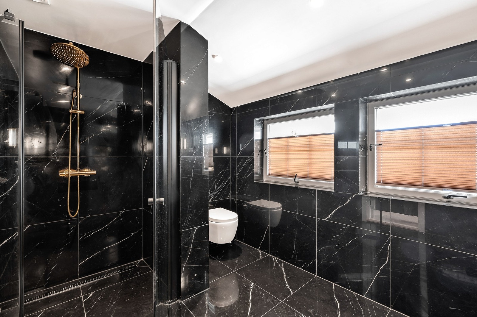 Dusjhjørne med glassdør og regnfallsdusj. Vegghengt toalett med innebygget sisterne. Galleribilde