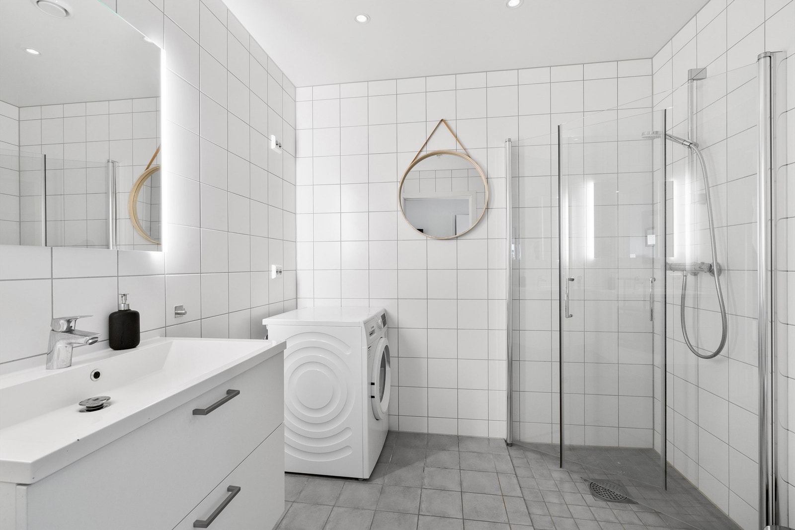 Bad 1. Flislagt gulv med gulvvarme og flislagte vegger. Vegghengt toalett og servantinnredning med skuffer. Speil med sidelys. Her er det opplegg for vaskemaskin. Galleribilde