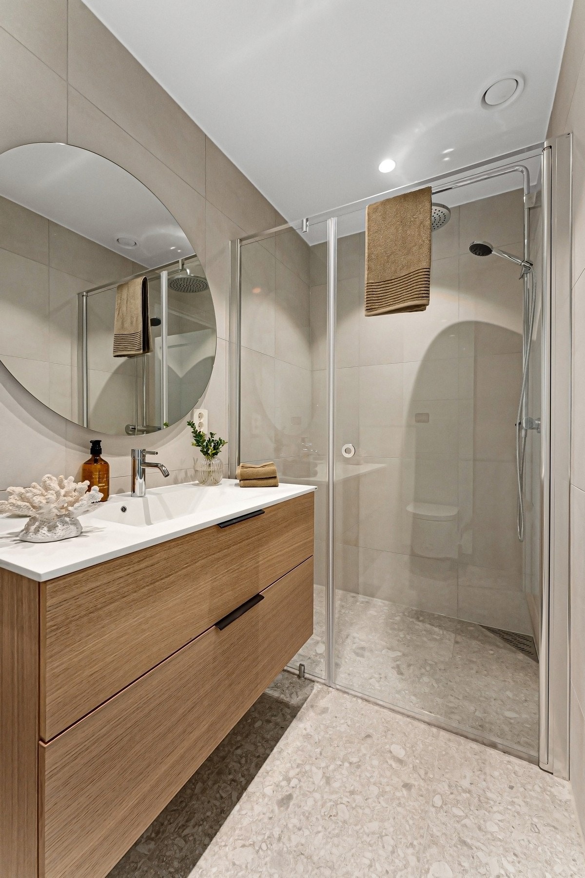 Smakfullt innredet baderom med lekre fliser, stor dusjnisje med glassdører og baderomsinnredning med skuffer i eik Galleribilde