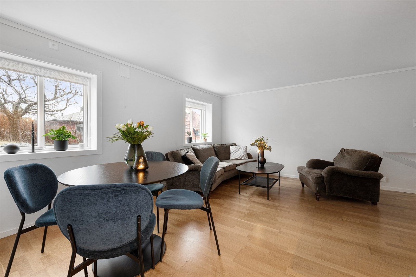 Romslig stue med parkett på gulv og vindusoverflater som gir godt med naturlig lysinnslipp. Galleribilde