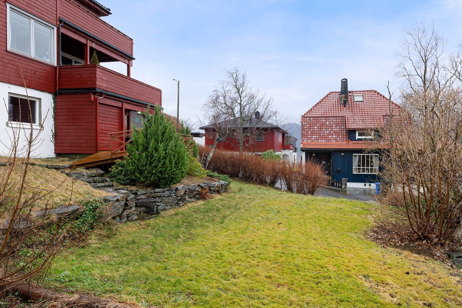 Stor hage som fellesareal med adkomst via trapp av stein ned fra terrasse. Galleribilde
