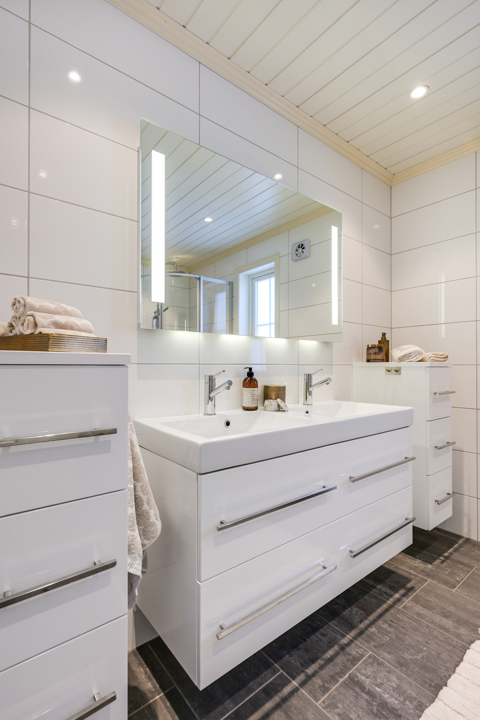 Innredningen består av dobbel servant med hvite skuffer, to matchende skuffeseksjoner og et stort speil med belysning integrert Galleribilde