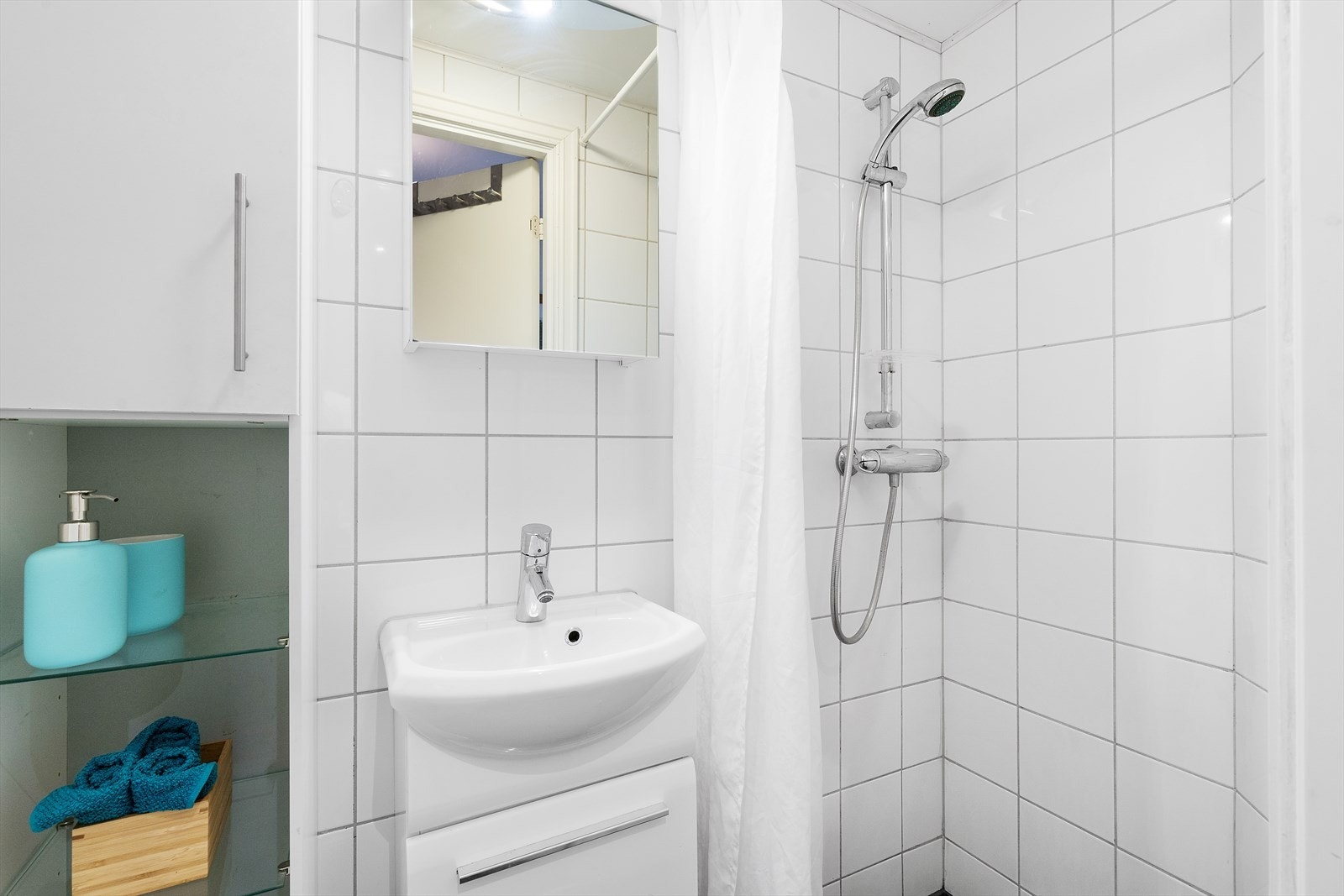Badet i underetasjen har grå gulvfliser, hvite veggfliser, servantskap med heldekkende servant, speilskap og vegghengt toalett. Galleribilde