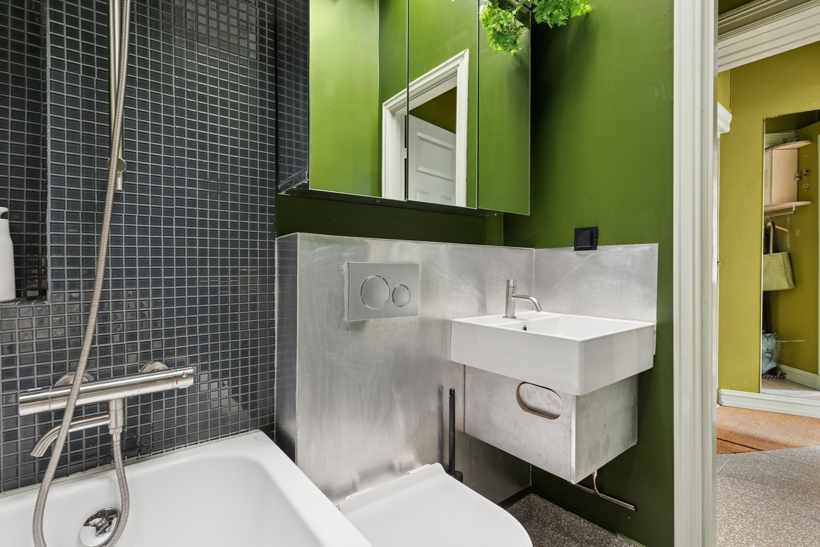 Flislagte gulv med varmekabler. Badet består av vegghengt wc, servant m/underskap, overskap m/speilfronter og overlys og innfliset badekar m/dusjgarnityr. Galleribilde