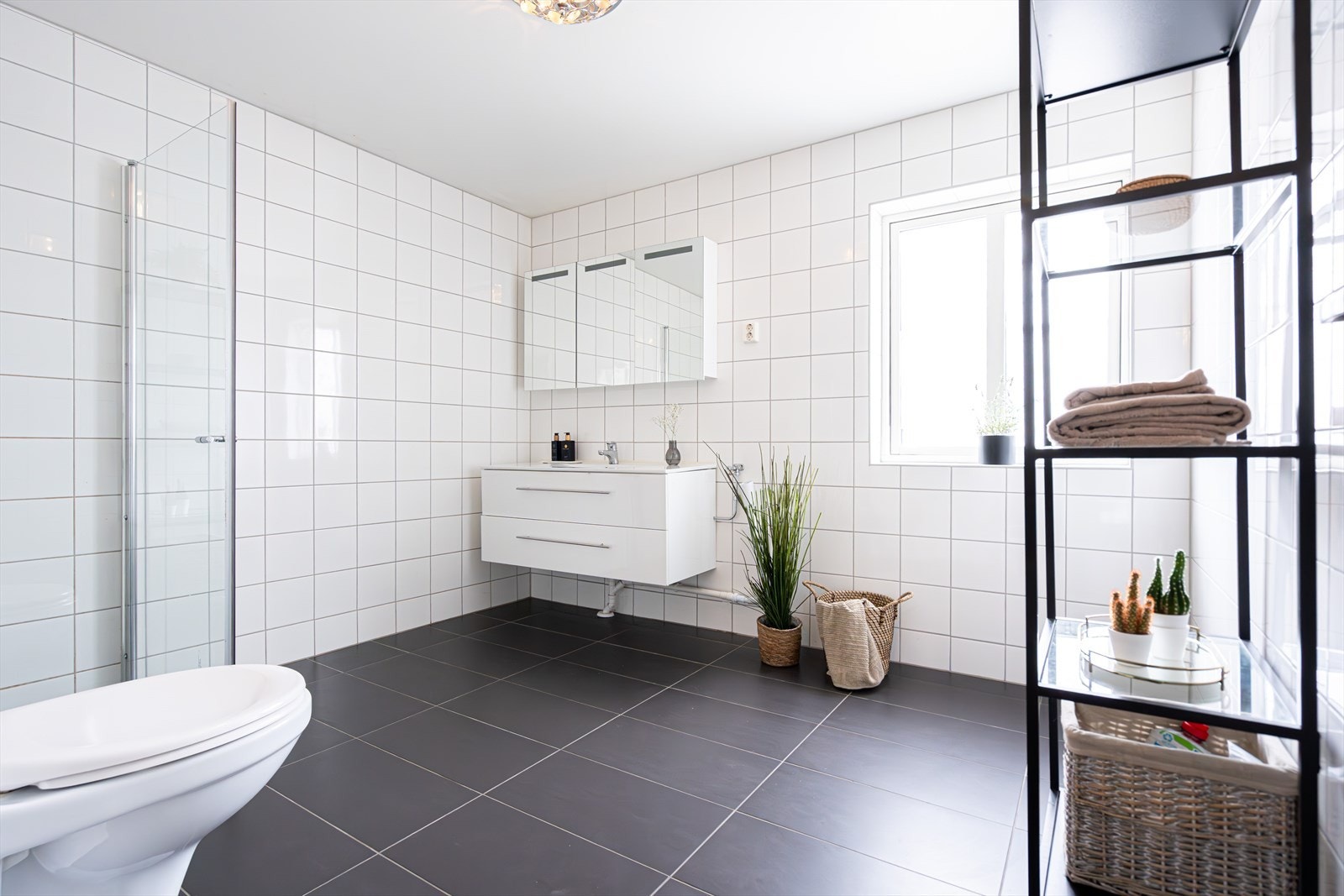 BAD I | Baderommet har et tidløst uttrykk med mørke fliser på gulvet med gulvvarme og lyse fliser på veggene. Galleribilde